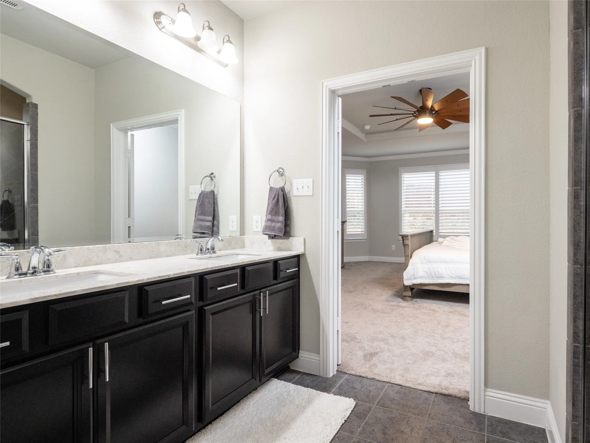 Dual vanity with dark wood-finish cabinetry, light-toned countertop, and chrome fixtures