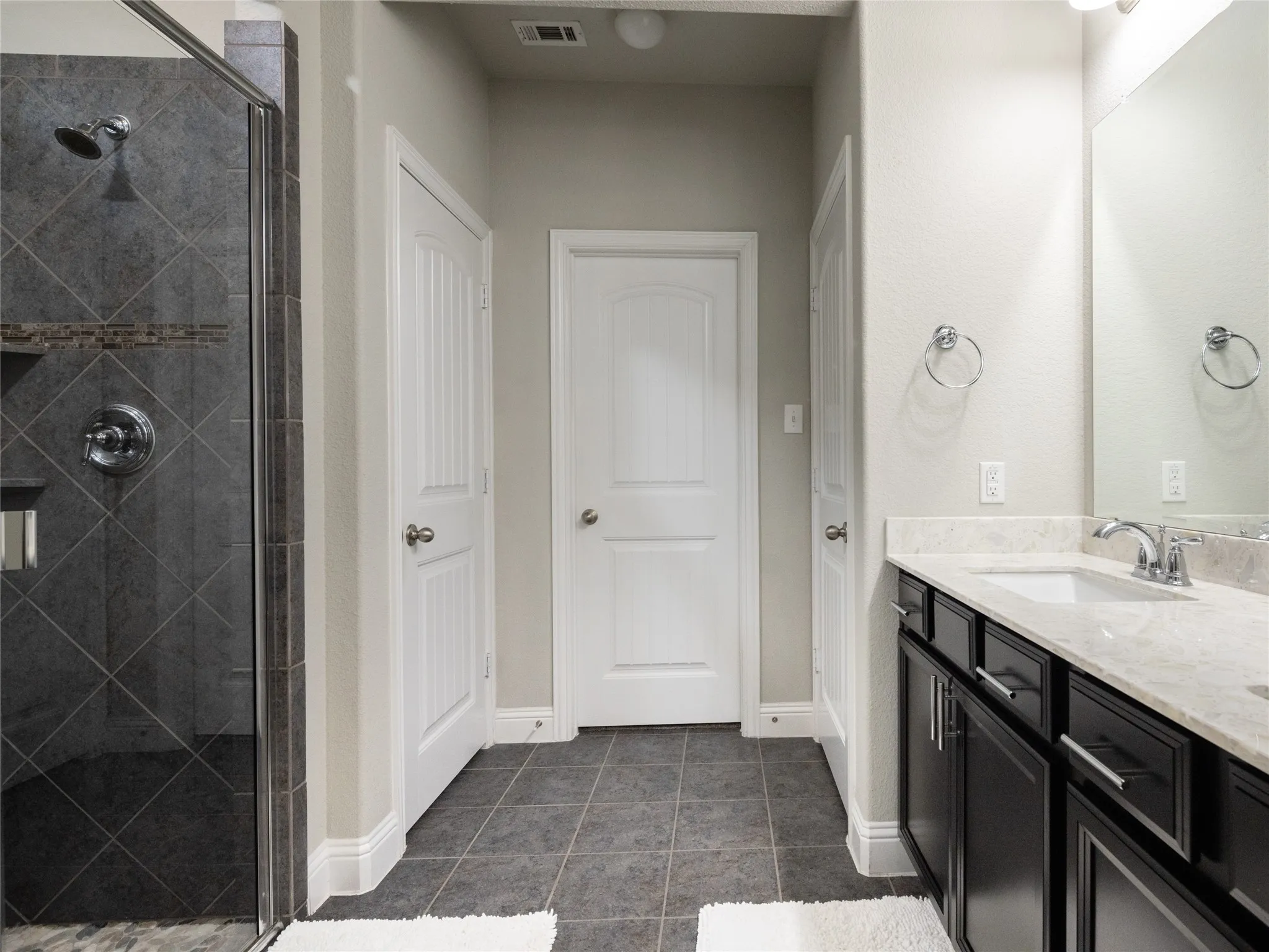 Walk-in shower with dark gray diagonal tile and a decorative accent band