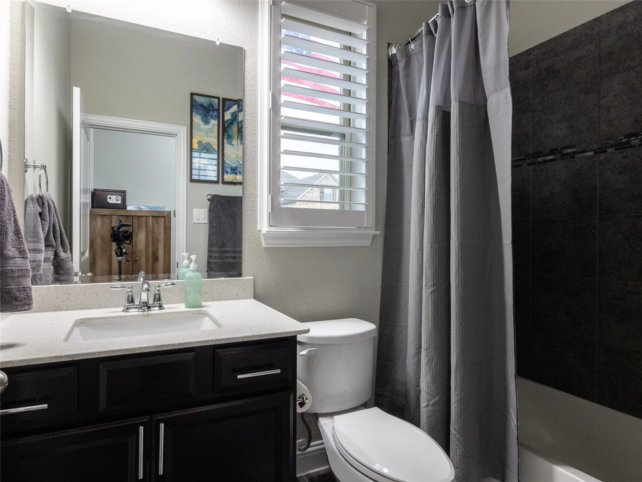 Dark wood-finish vanity with a light-toned countertop, undermount sink, and chrome fixtures