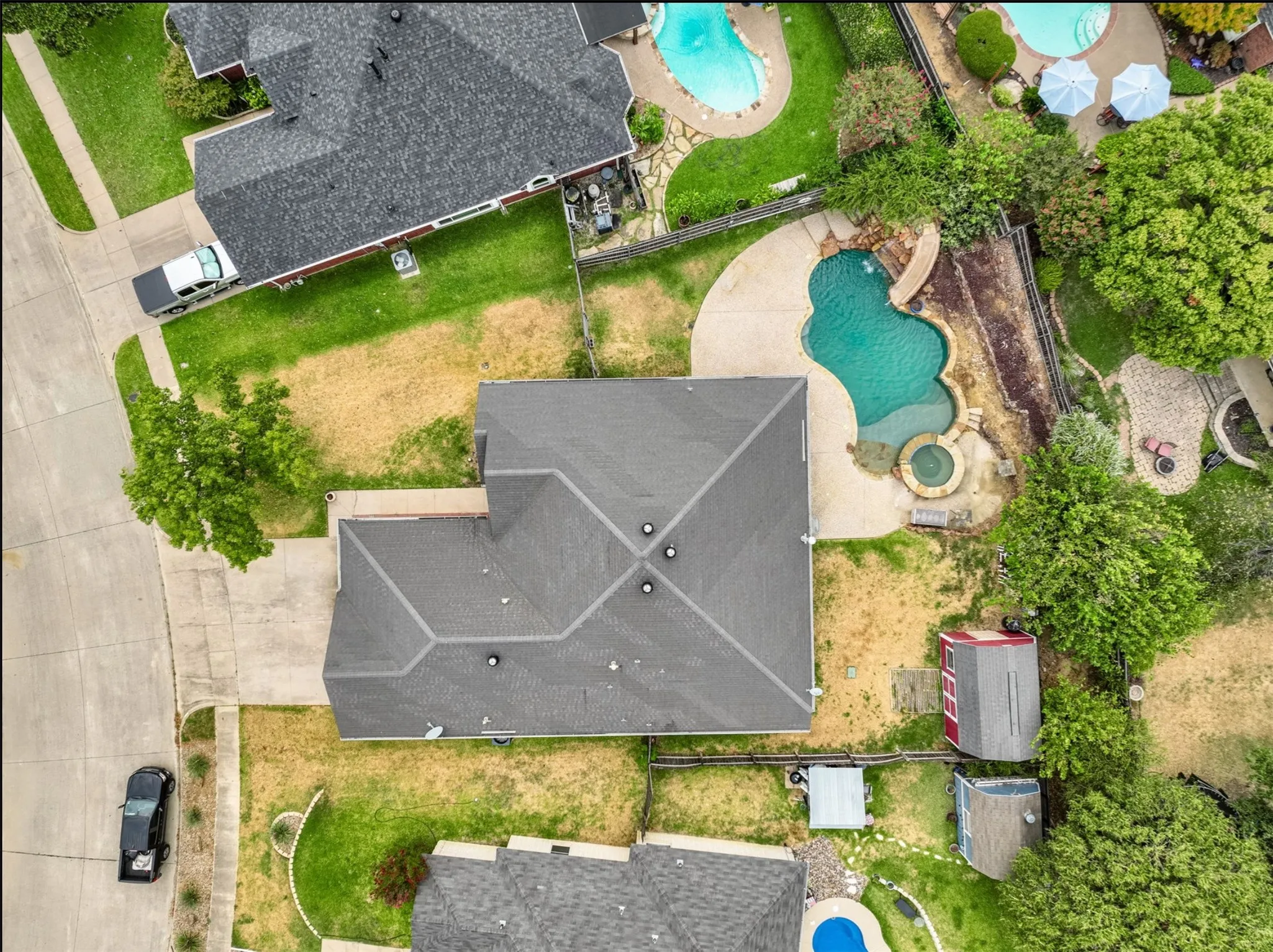 Asphalt shingle roofing, concrete driveway, concrete patio, swimming pool with spa, outbuilding