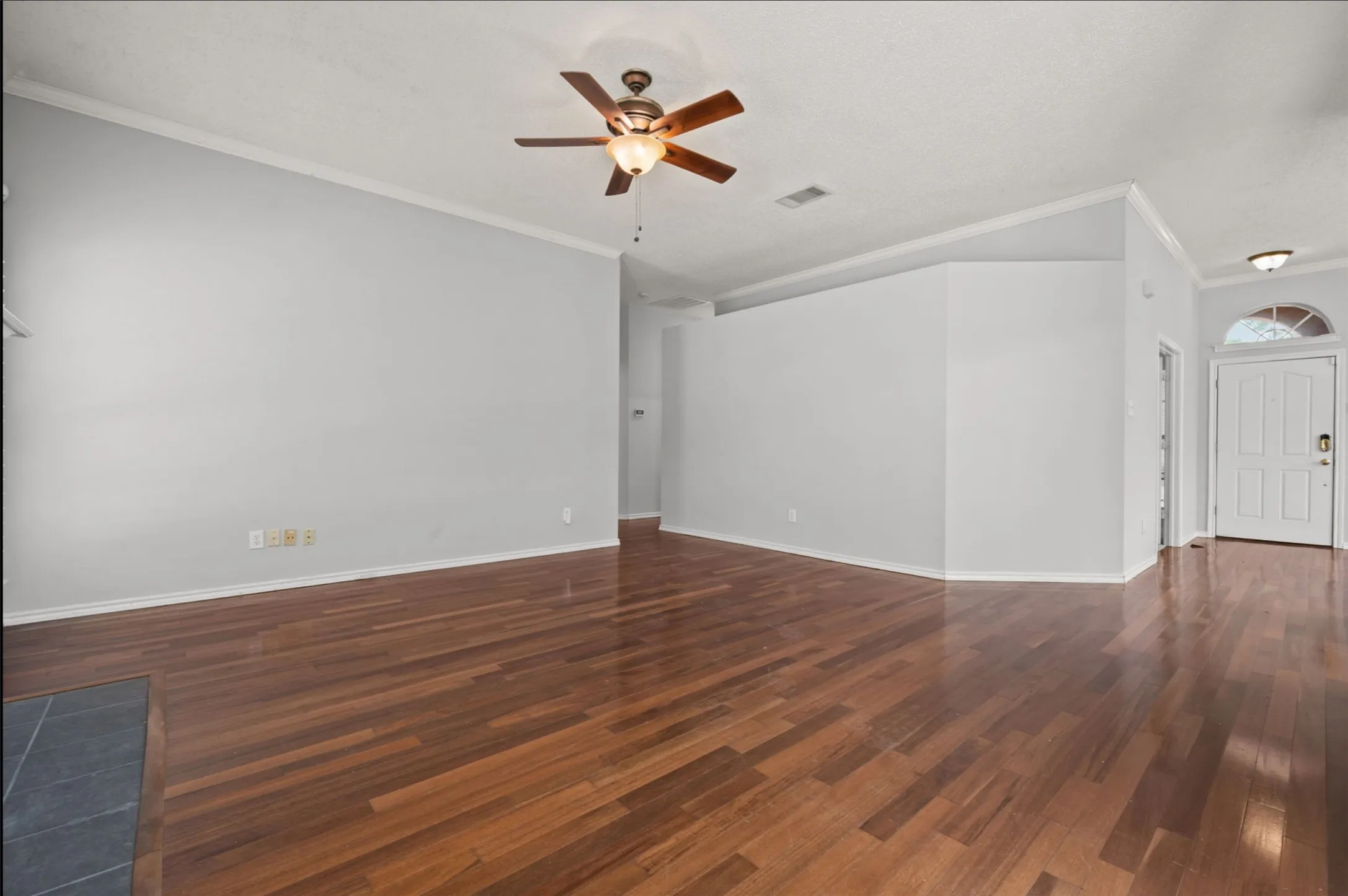 Wood flooring throughout, high ceiling with a ceiling fan, and crown molding