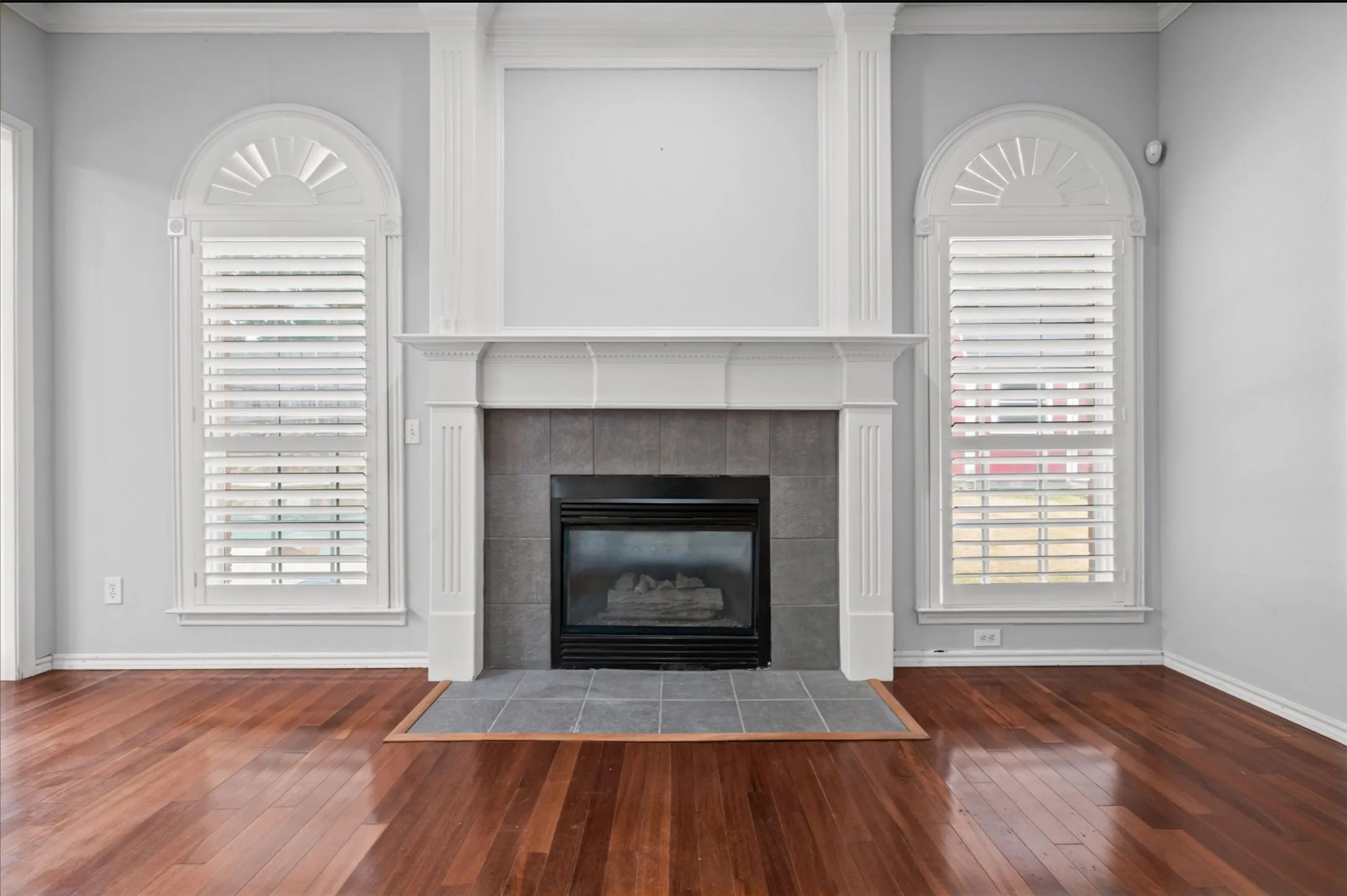  gas log Fireplace, wood flooring, Arch windows with plantation shutters