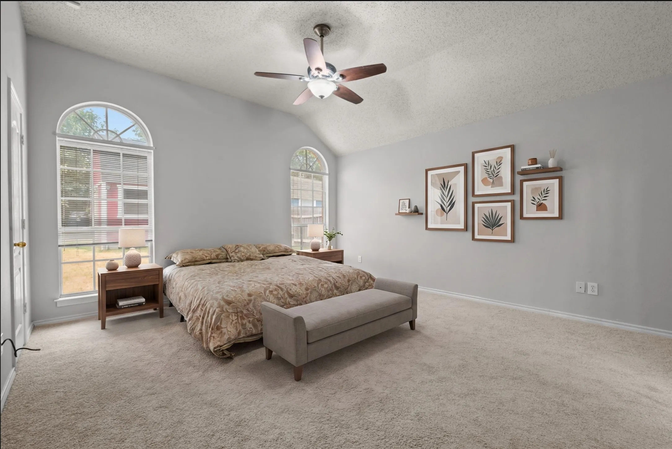 High ceiling with a ceiling fan, two arched windows, light gray walls, and new carpeted flooring. Built in vanity