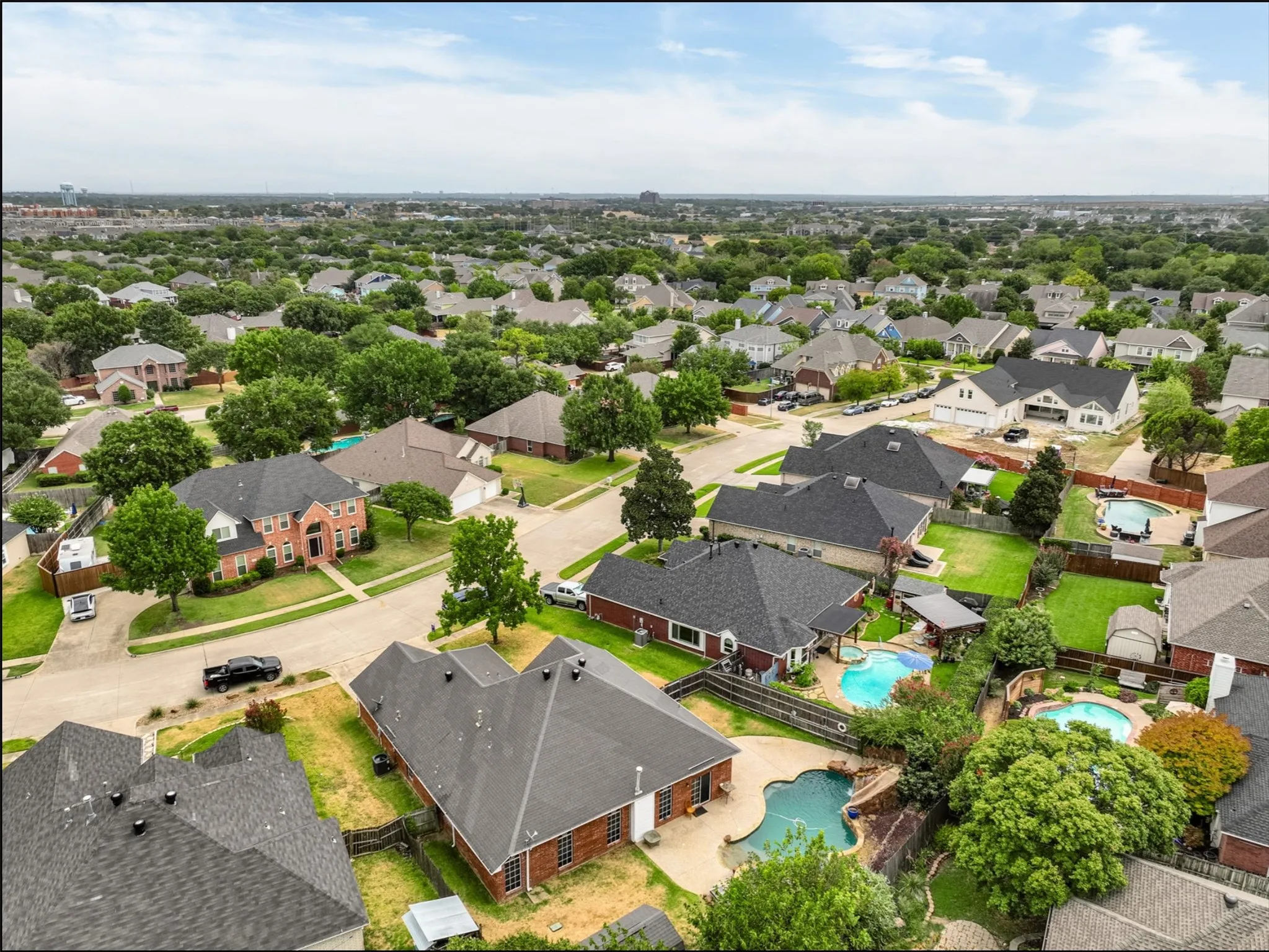 Expansive neighborhood with diverse architectural styles, mature trees, and multiple properties featuring private swimming pools
