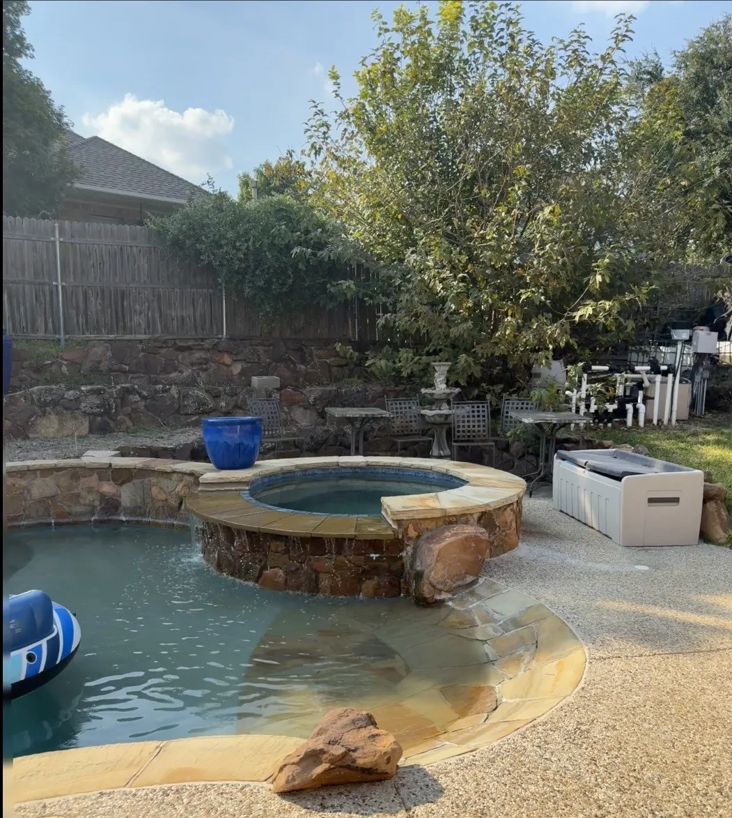 Swimming pool with integrated spa, walk in beach entry, graduated depths to 8 ft. Flagstone coping, and a rock-faced spa exterior