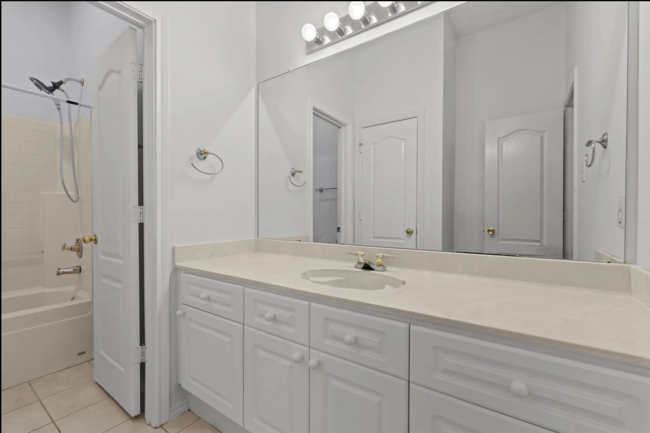 Long vanity with an integrated sink, ample drawers and cabinets expansive mirror, and overhead strip lighting and large separate linen closet
