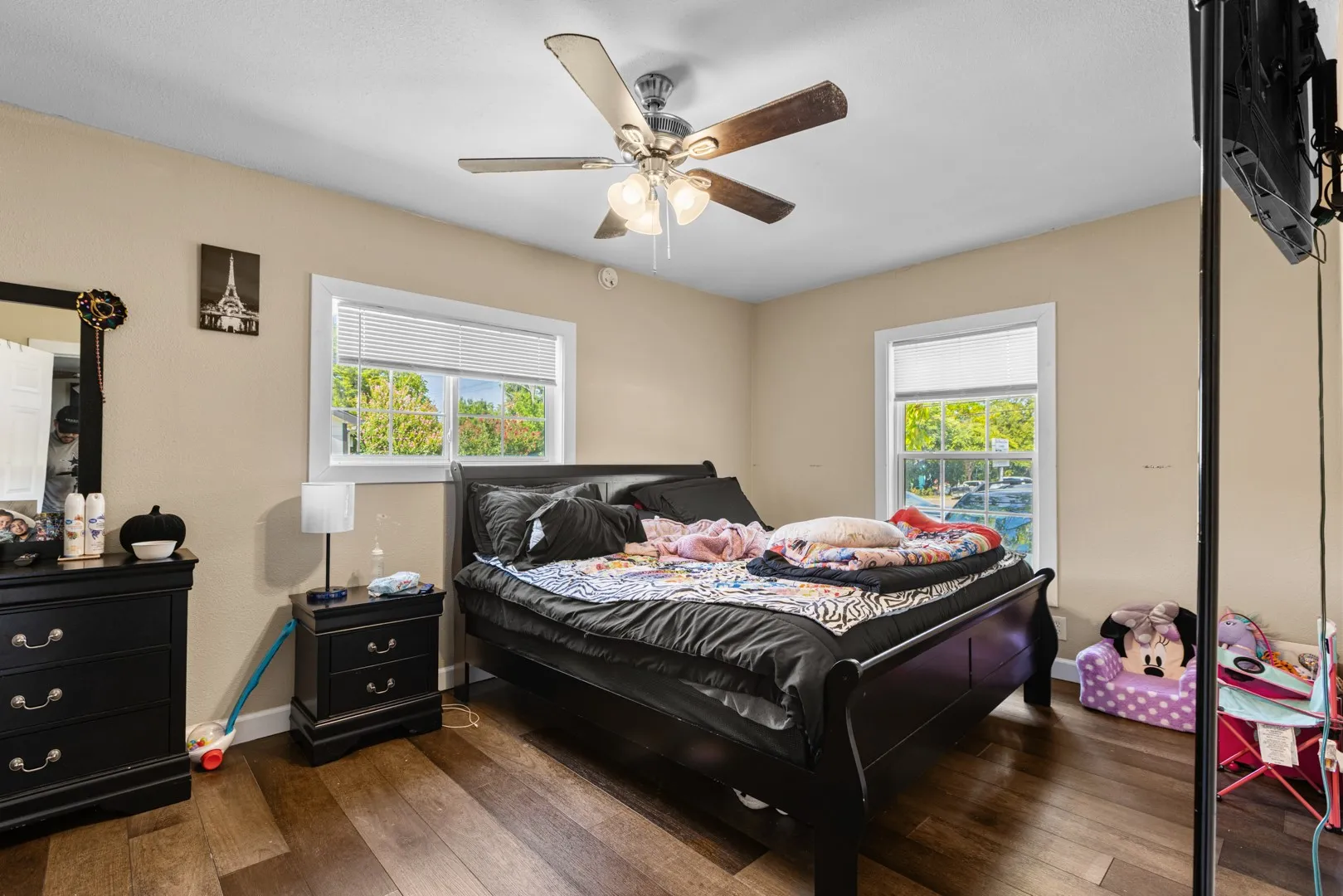 Hardwood-style flooring, a ceiling fan with integrated lighting, and white window frames with blinds