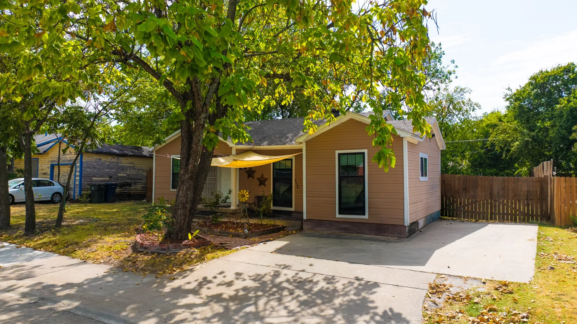 Siding exterior, concrete driveway, wood privacy fence, and mature trees