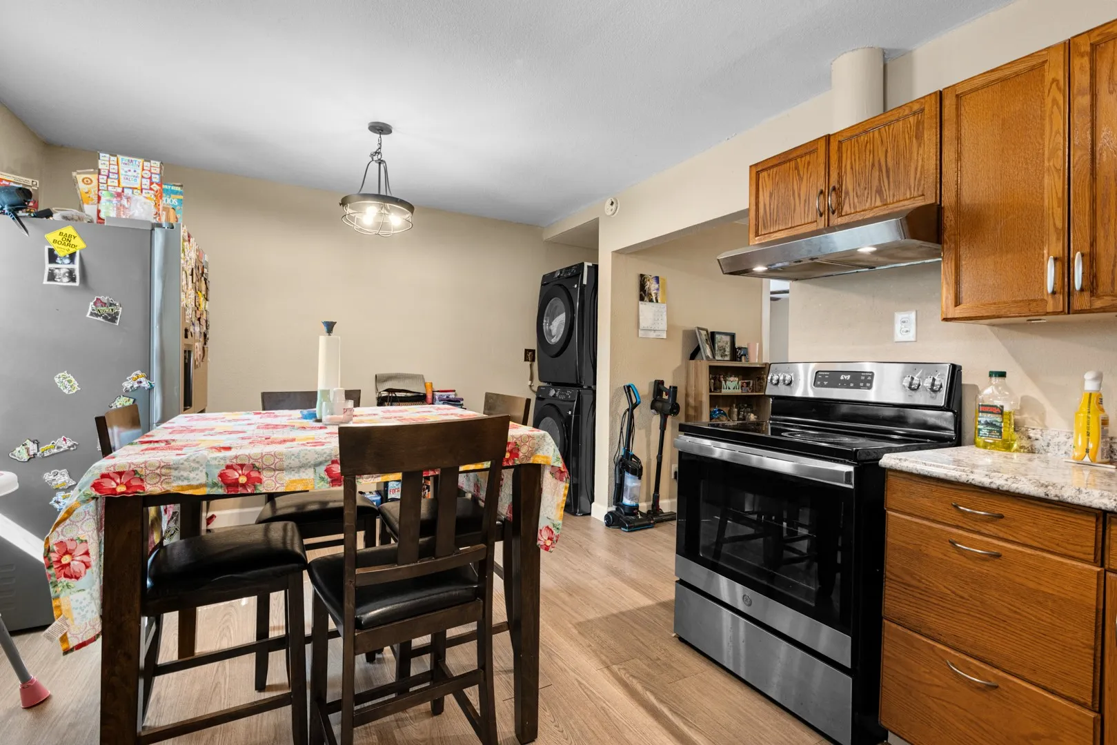 Wood-finish flooring, wood cabinetry, stainless steel range, and light-toned countertops