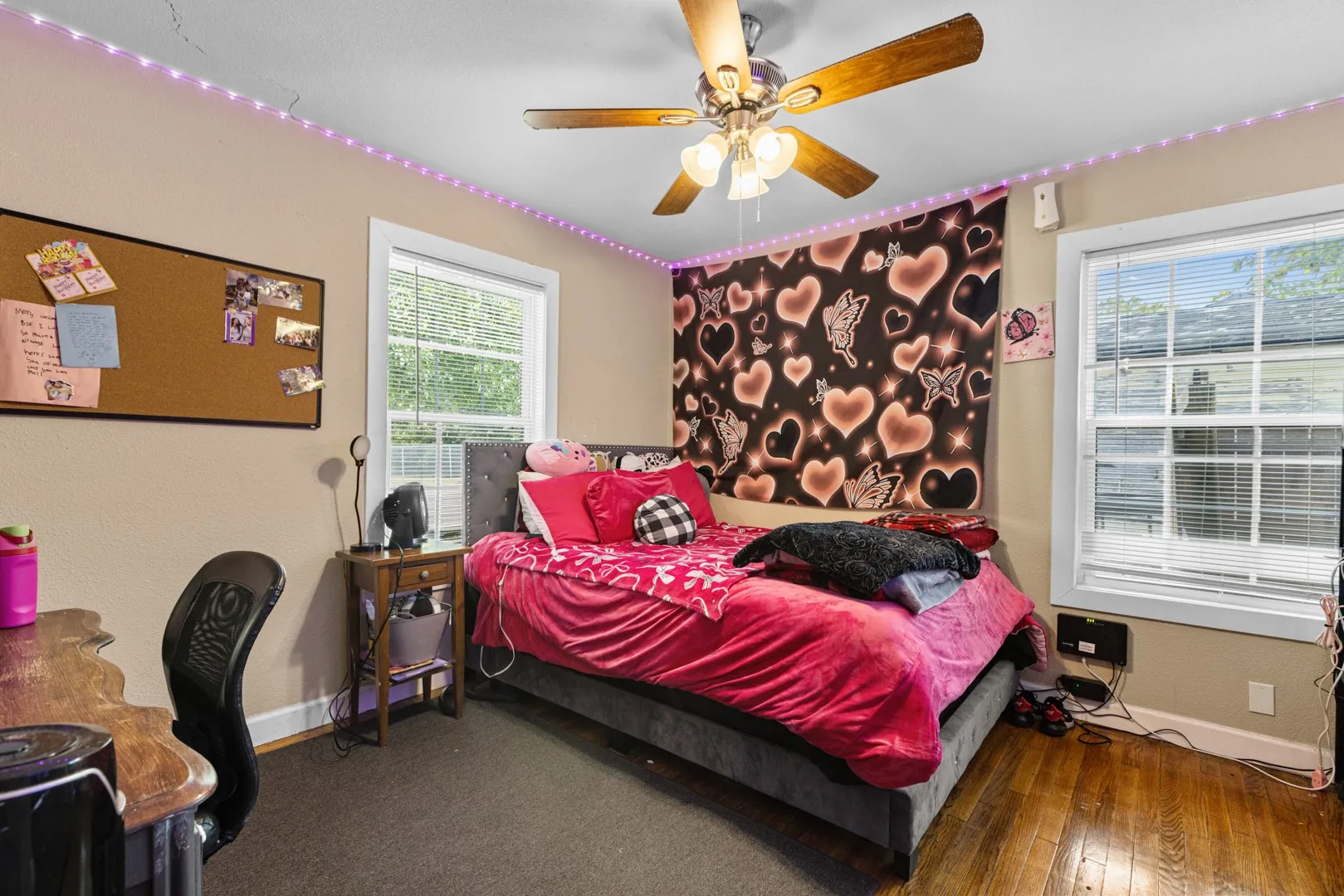 Hardwood flooring, ceiling fan, and two windows with blinds