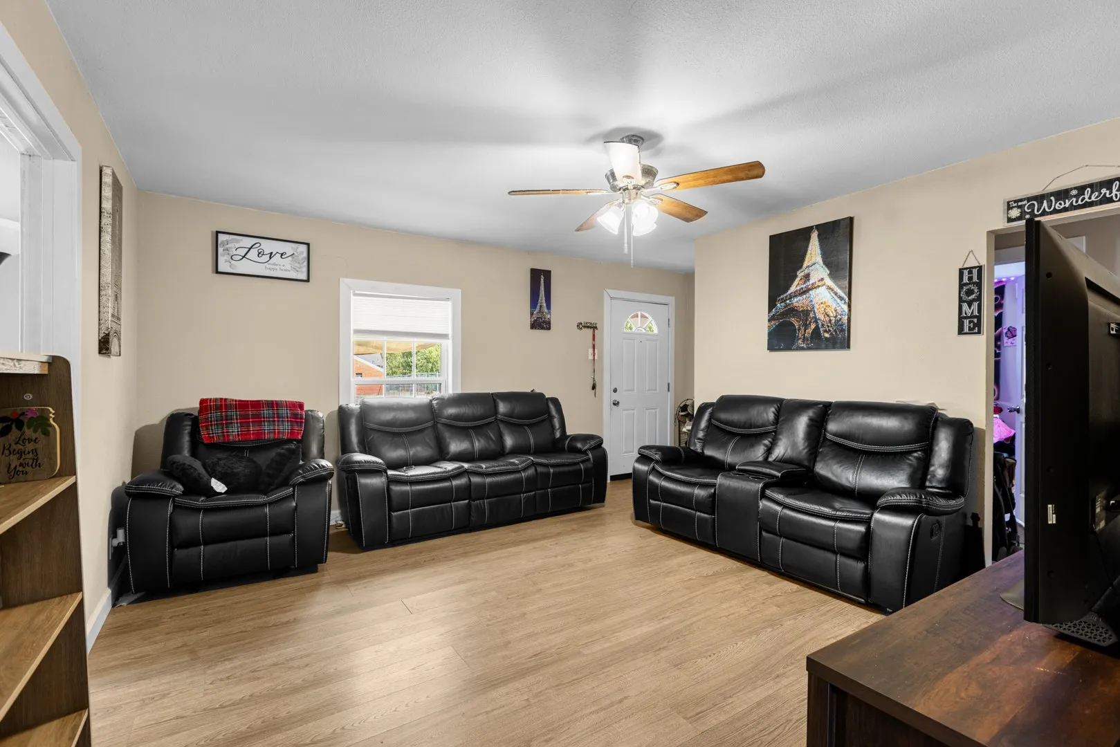 Wood-finish flooring, ceiling fan with light fixture, light-colored wall paint, white trim work, and a white entry door with a decorative glass insert