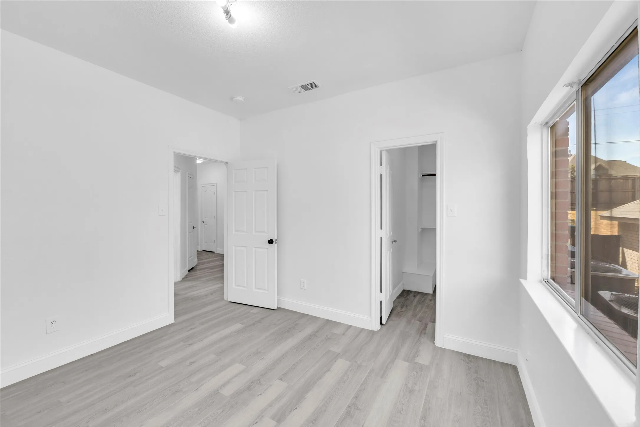 Light wood-finish flooring, white walls, and a window providing natural light