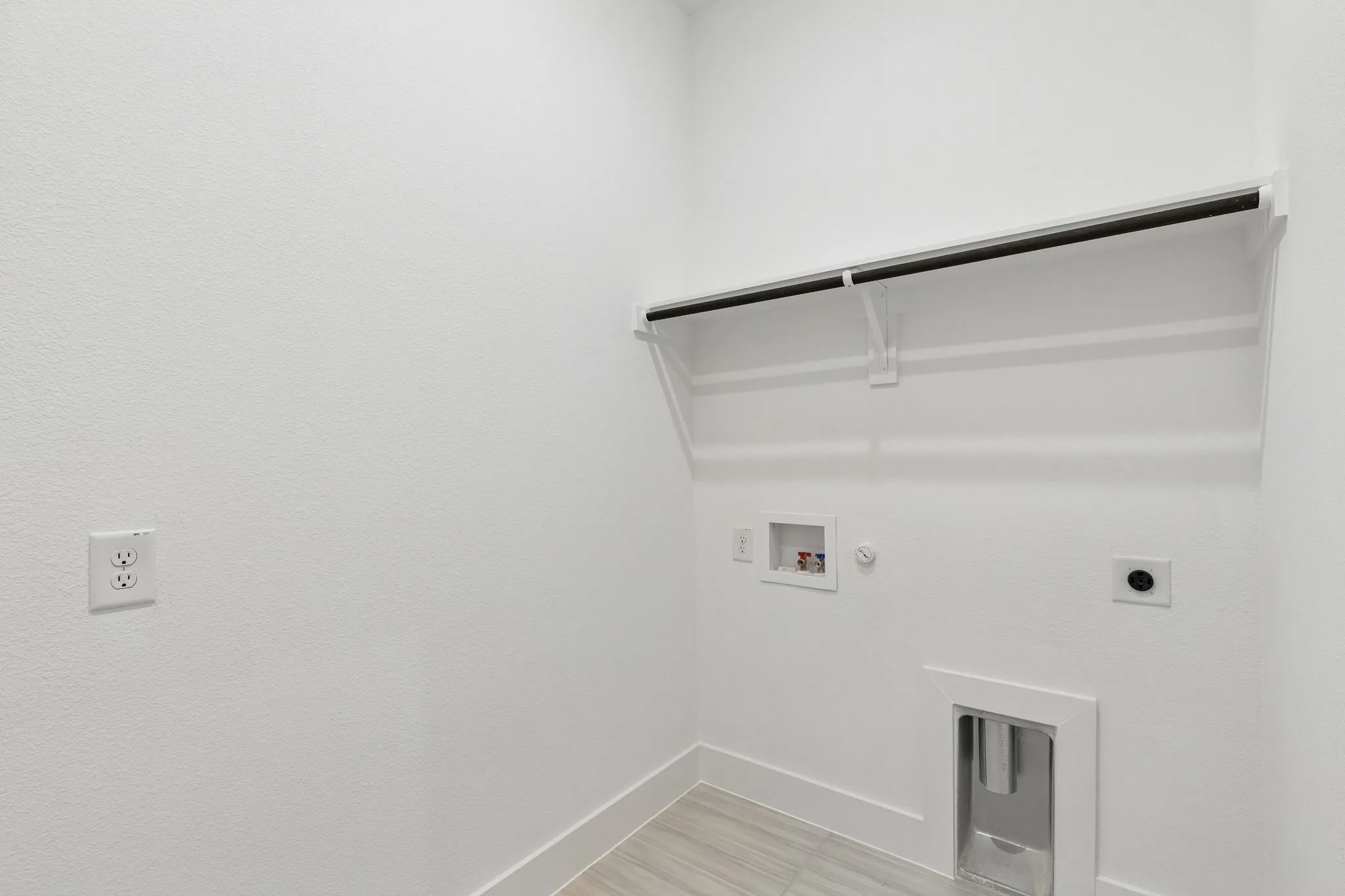 Laundry area featuring wood-finish flooring, built-in shelving, and a hanging rod