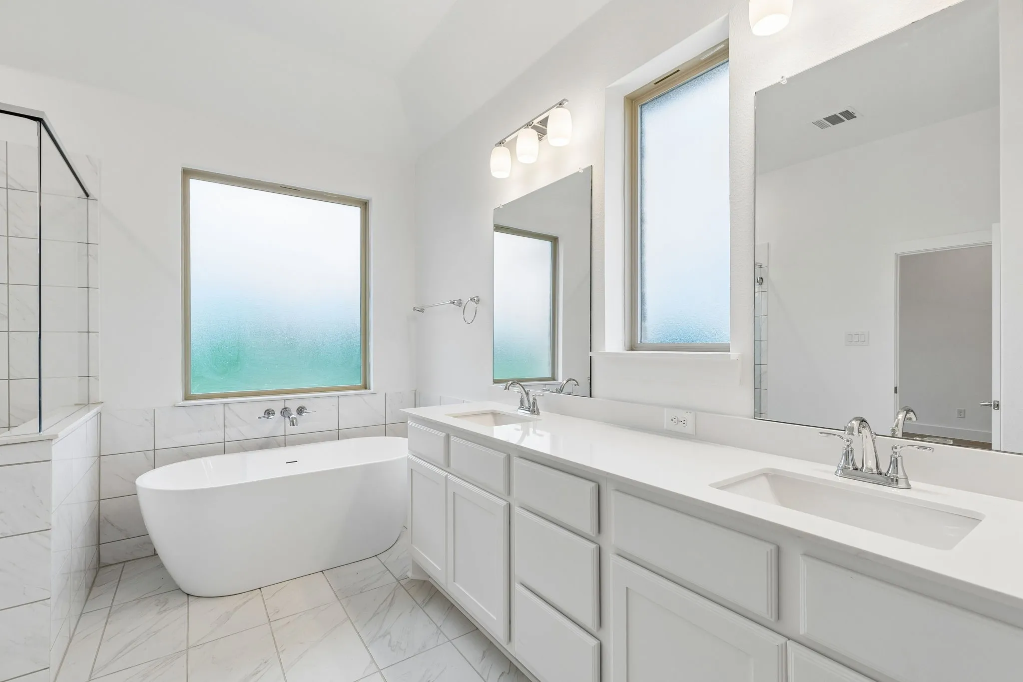 Dual vanity with undermount sinks, stone countertops, and chrome fixtures