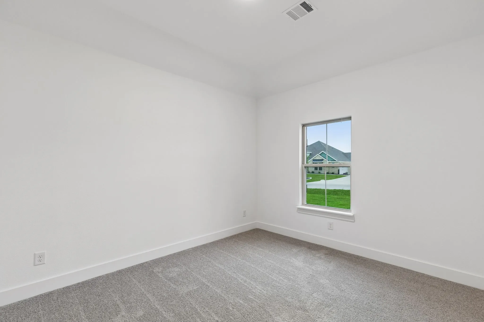 Wall-to-wall carpeting in a neutral tone, white painted walls, and a window providing natural illumination