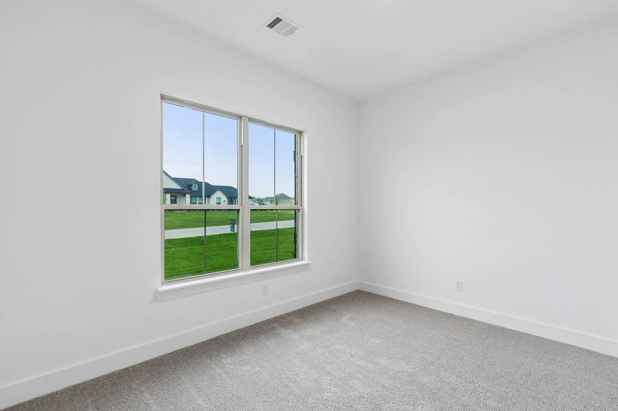 Carpeted flooring with white baseboards, white painted walls, and a large window with white trim
