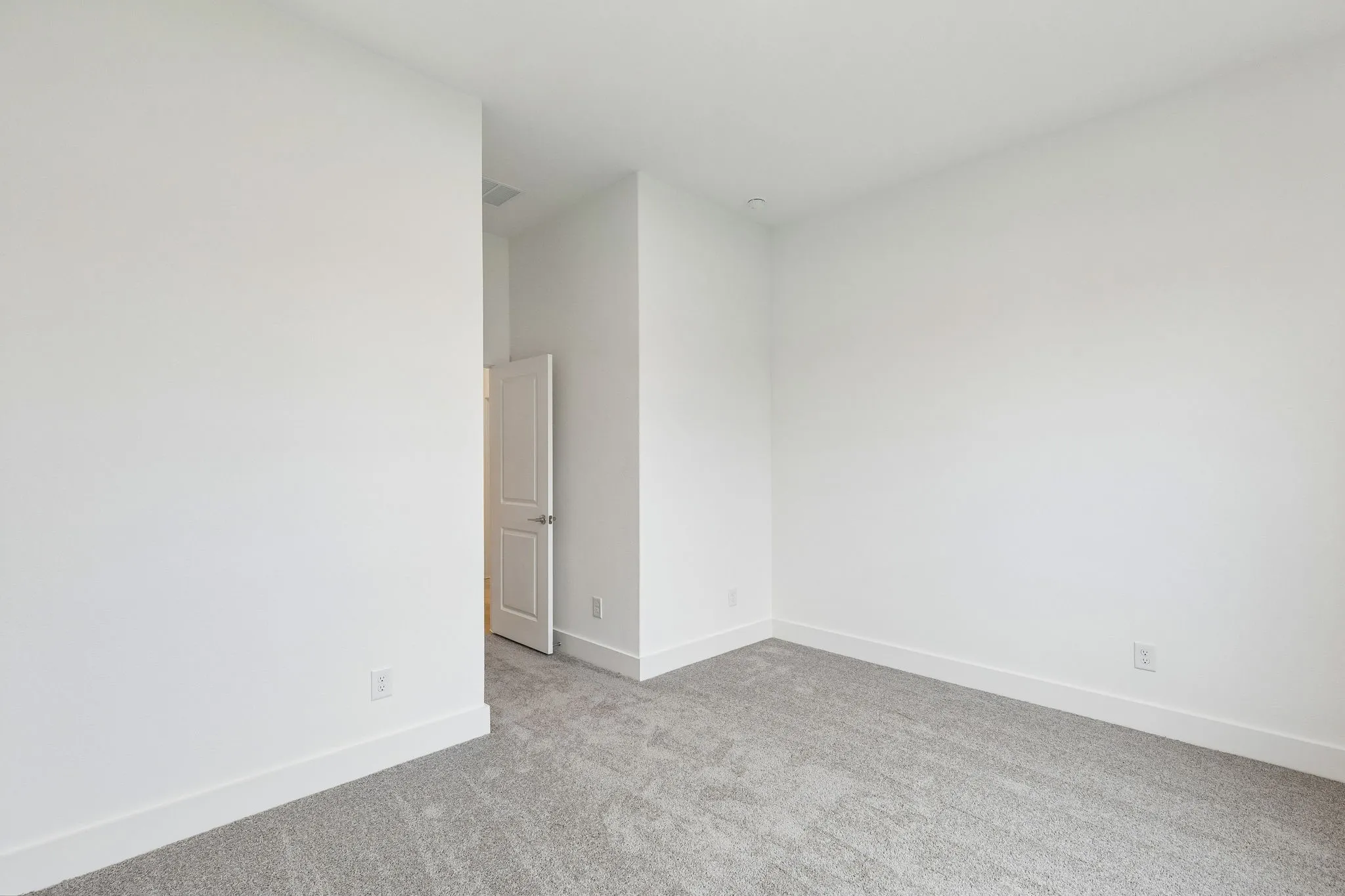 Neutral tone wall paint, light gray carpeting, crisp white trim, and a contemporary two-panel door