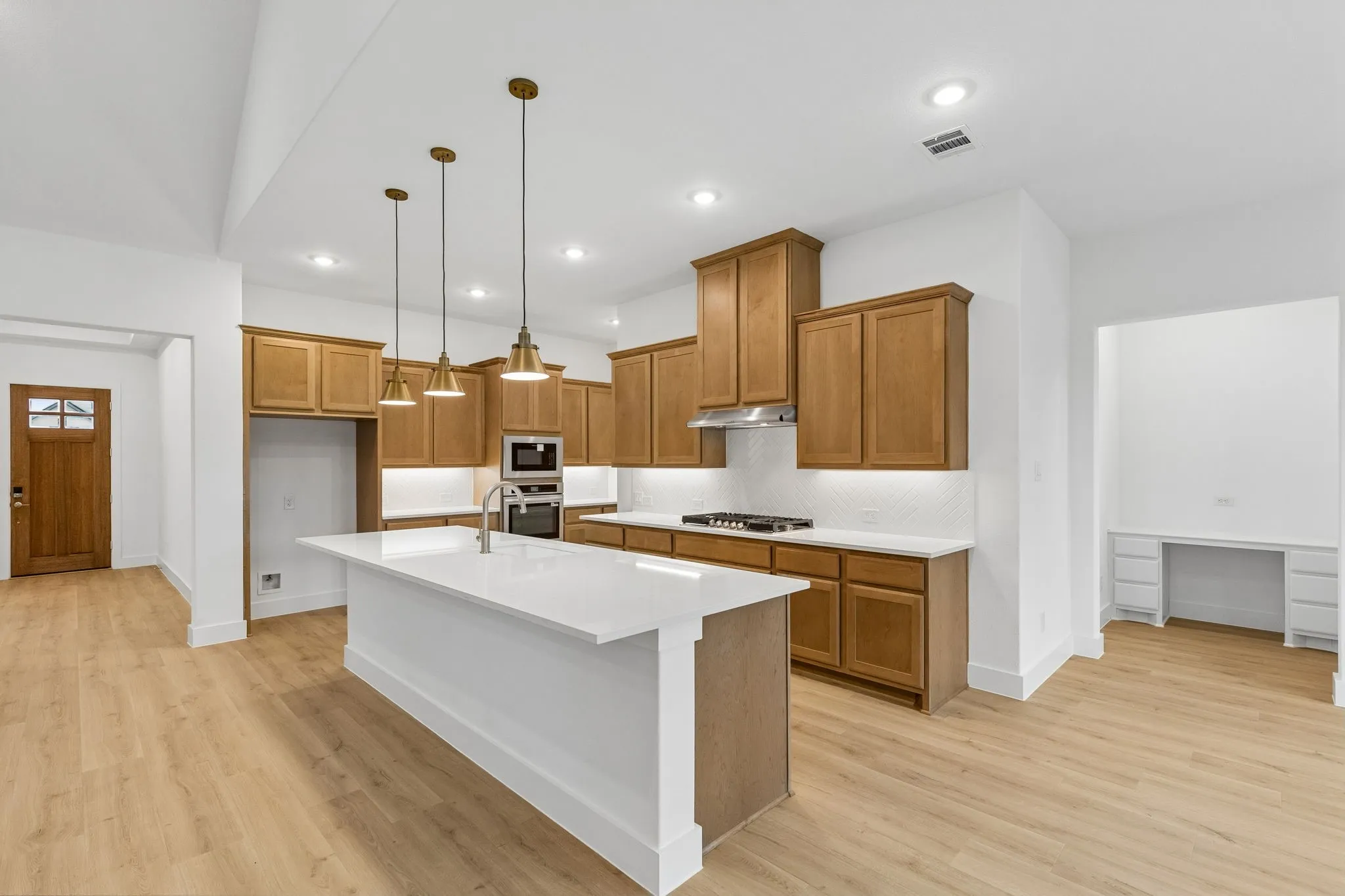 Kitchen featuring wood-finish cabinetry, a large center island with a white countertop, stainless steel appliances, and pendant lighting