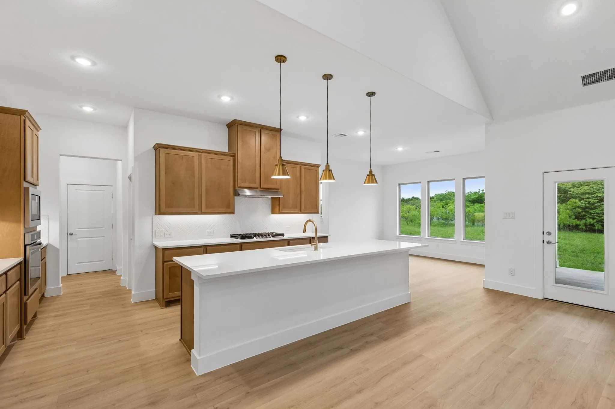 Kitchen featuring wood-finish cabinetry, a large center island with a white countertop, and pendant lighting