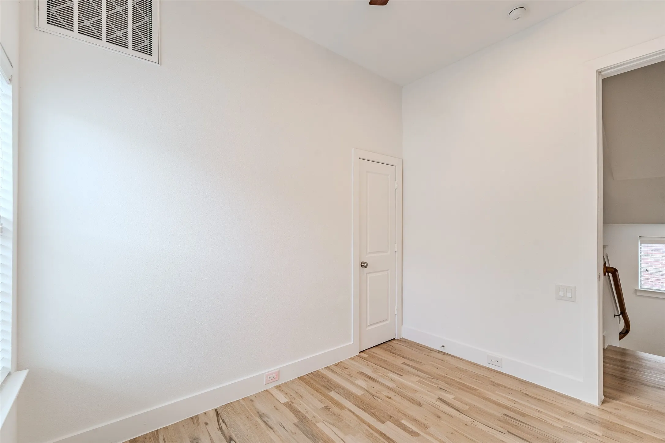 Hardwood flooring, painted walls, built-in door, and window with blinds