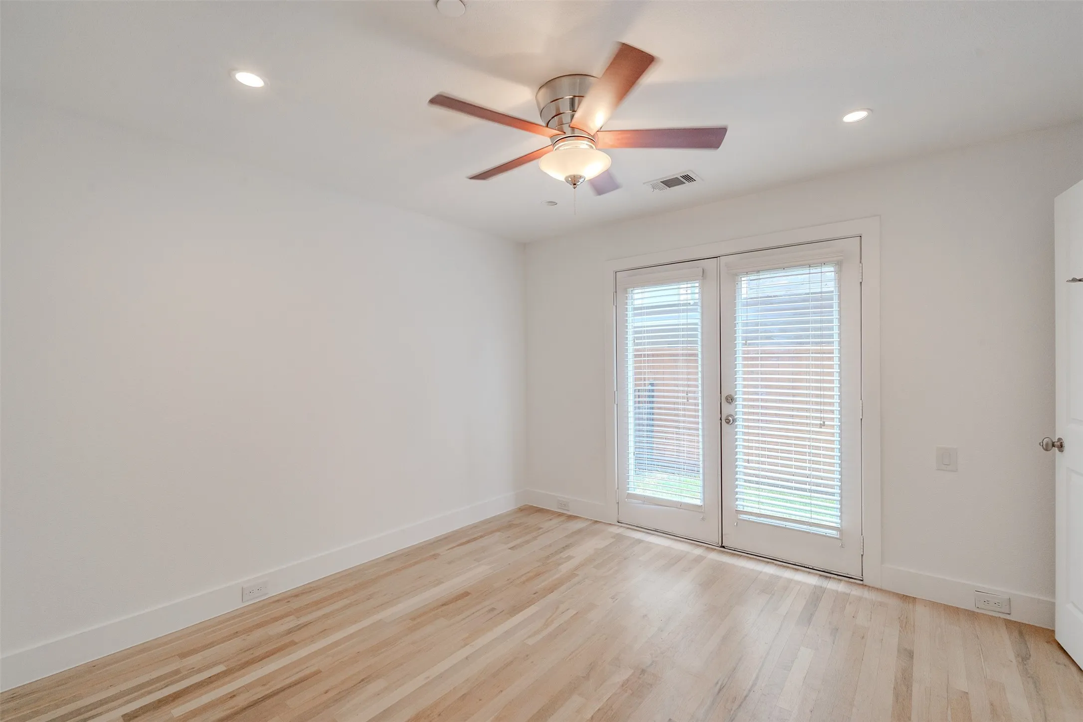 Wood-finish flooring, recessed lighting, ceiling fan, and double French doors with integrated blinds