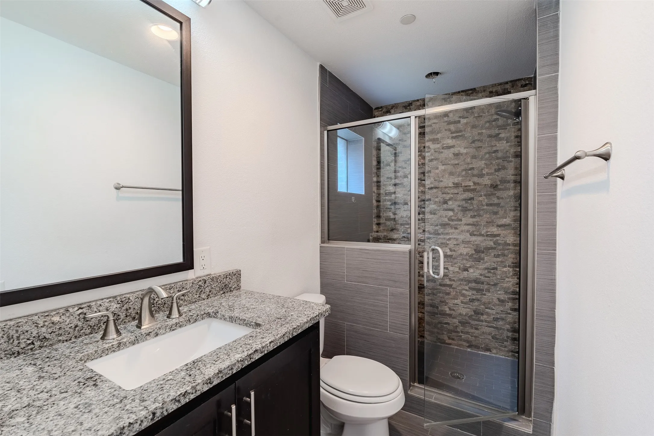 Vanity with a granite-style countertop, undermount sink, and dark wood-finish cabinetry