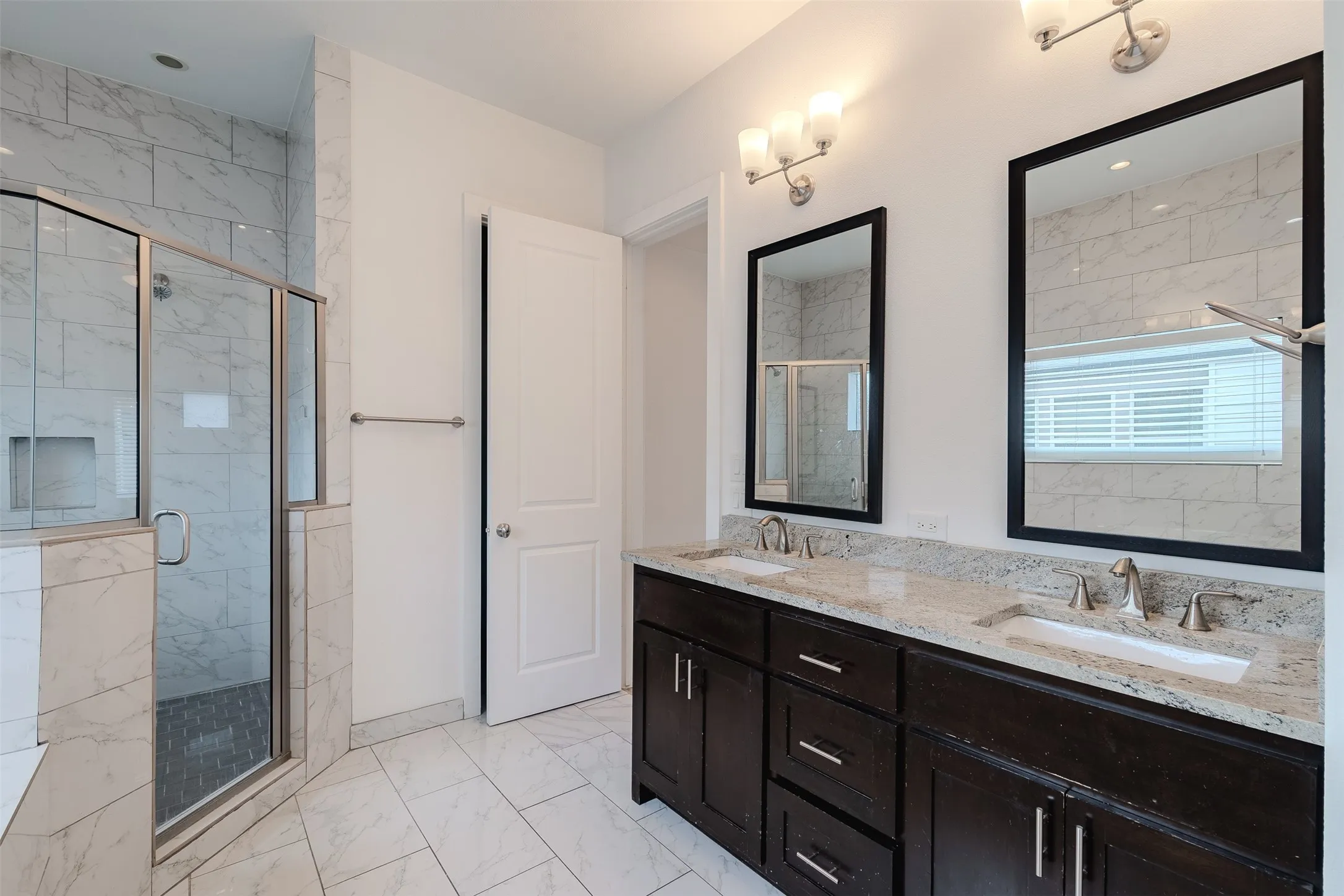 Dual vanity with granite countertops, undermount sinks, and dark wood-finish cabinetry