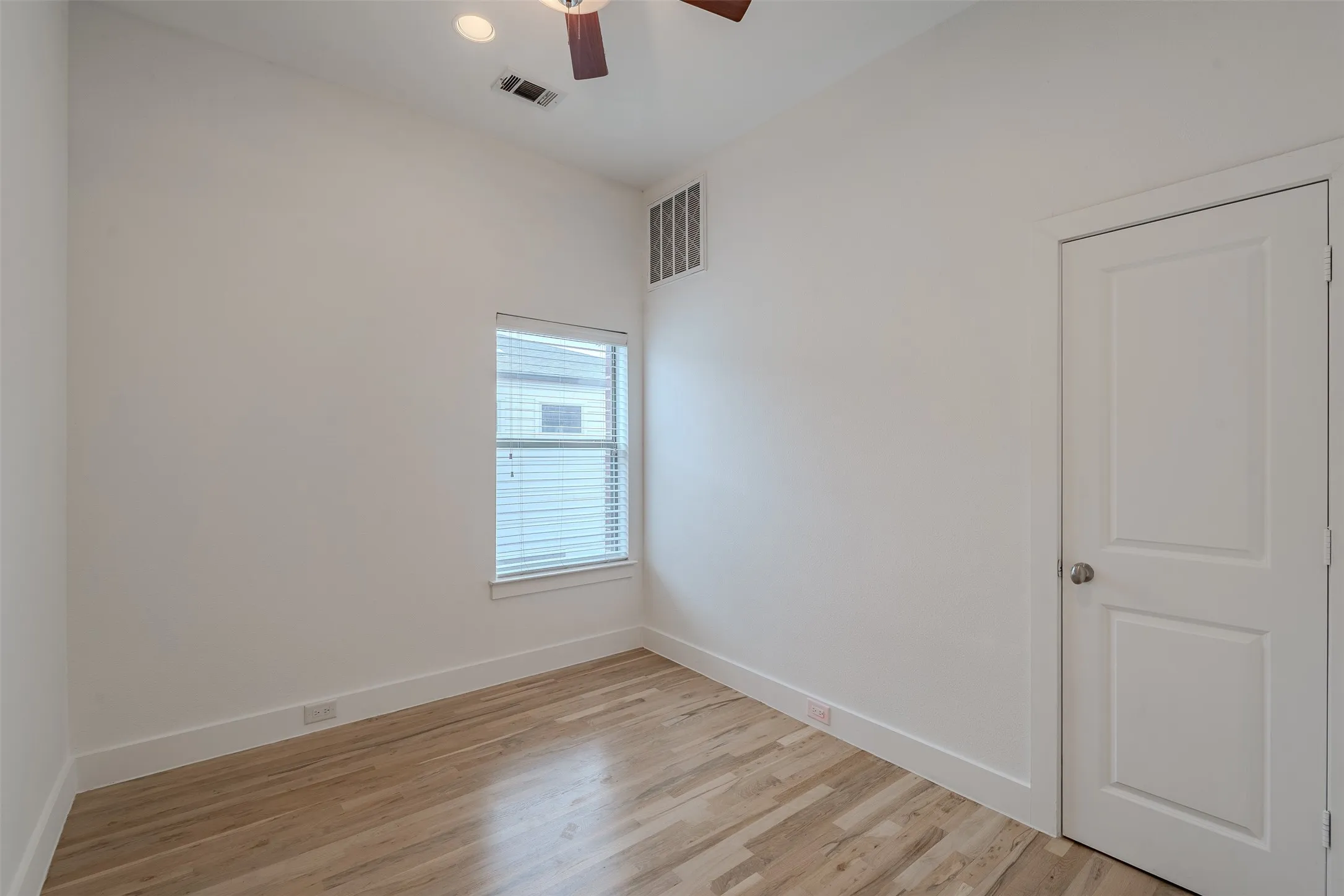 Vaulted ceiling, wood-finish flooring, ceiling fan, recessed lighting, and a two-panel interior door