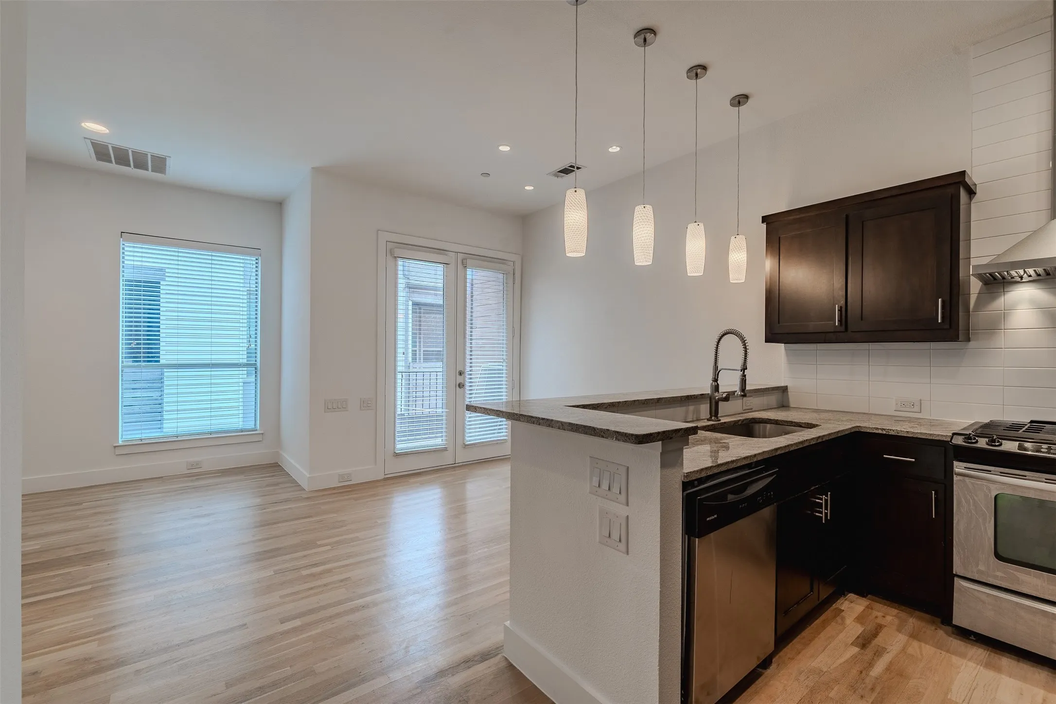 Kitchen featuring an undermount sink, stainless steel appliances, dark wood-finish cabinetry, and a white subway tile backsplash