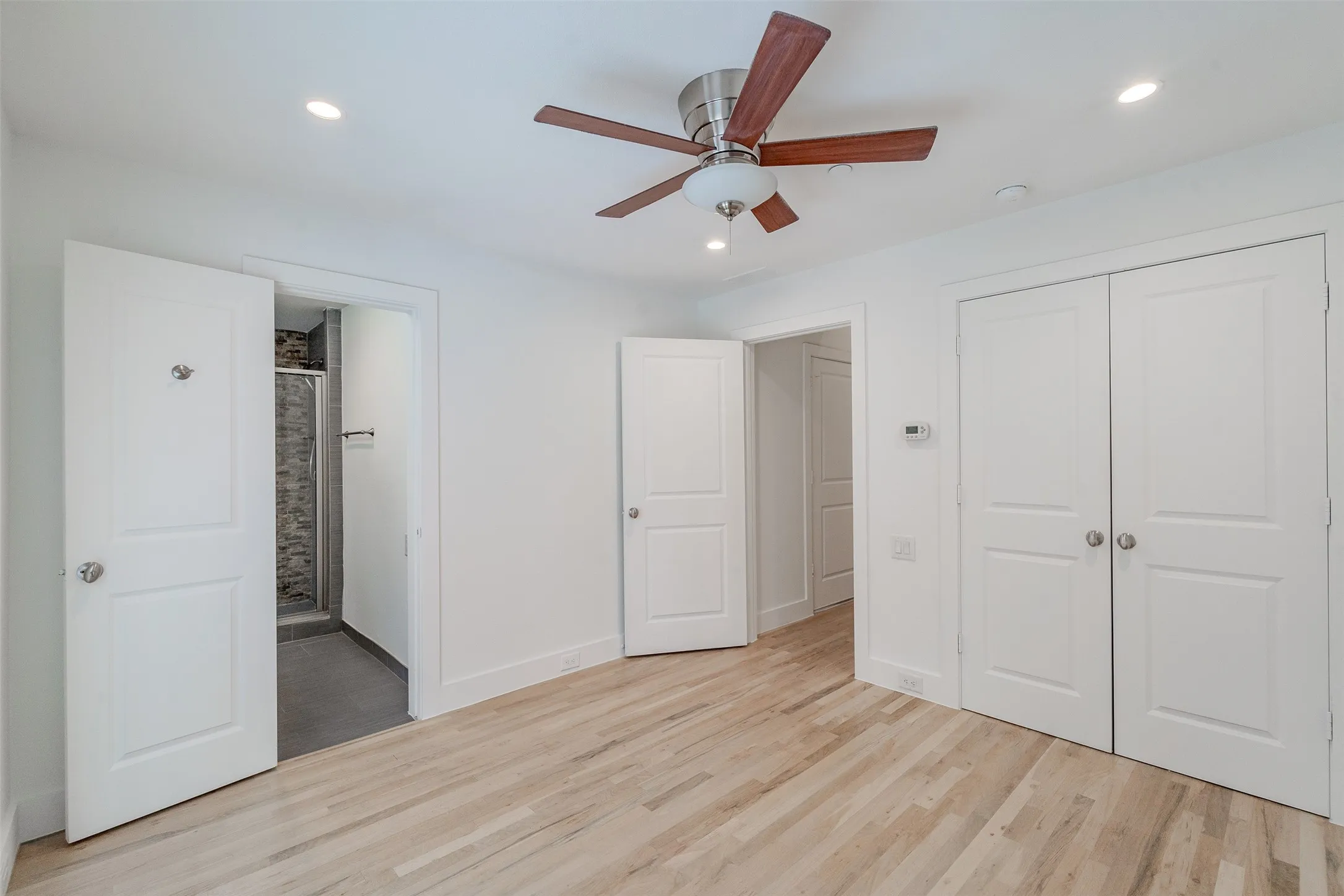Light wood-finish flooring, white walls, recessed lighting, and a ceiling fan with integrated lighting
