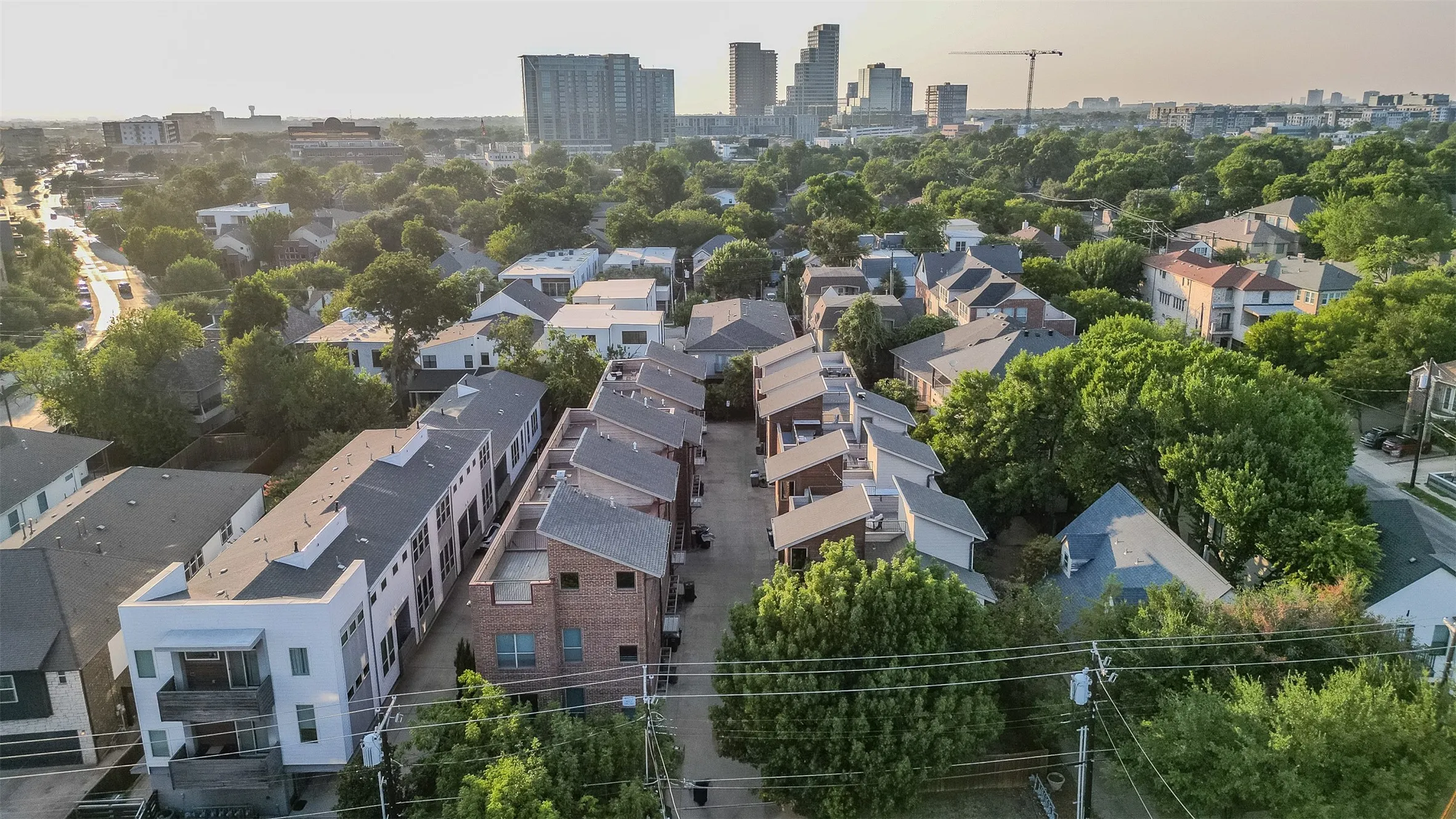 Urban neighborhood setting featuring mature trees and a mix of modern and traditional residential architecture