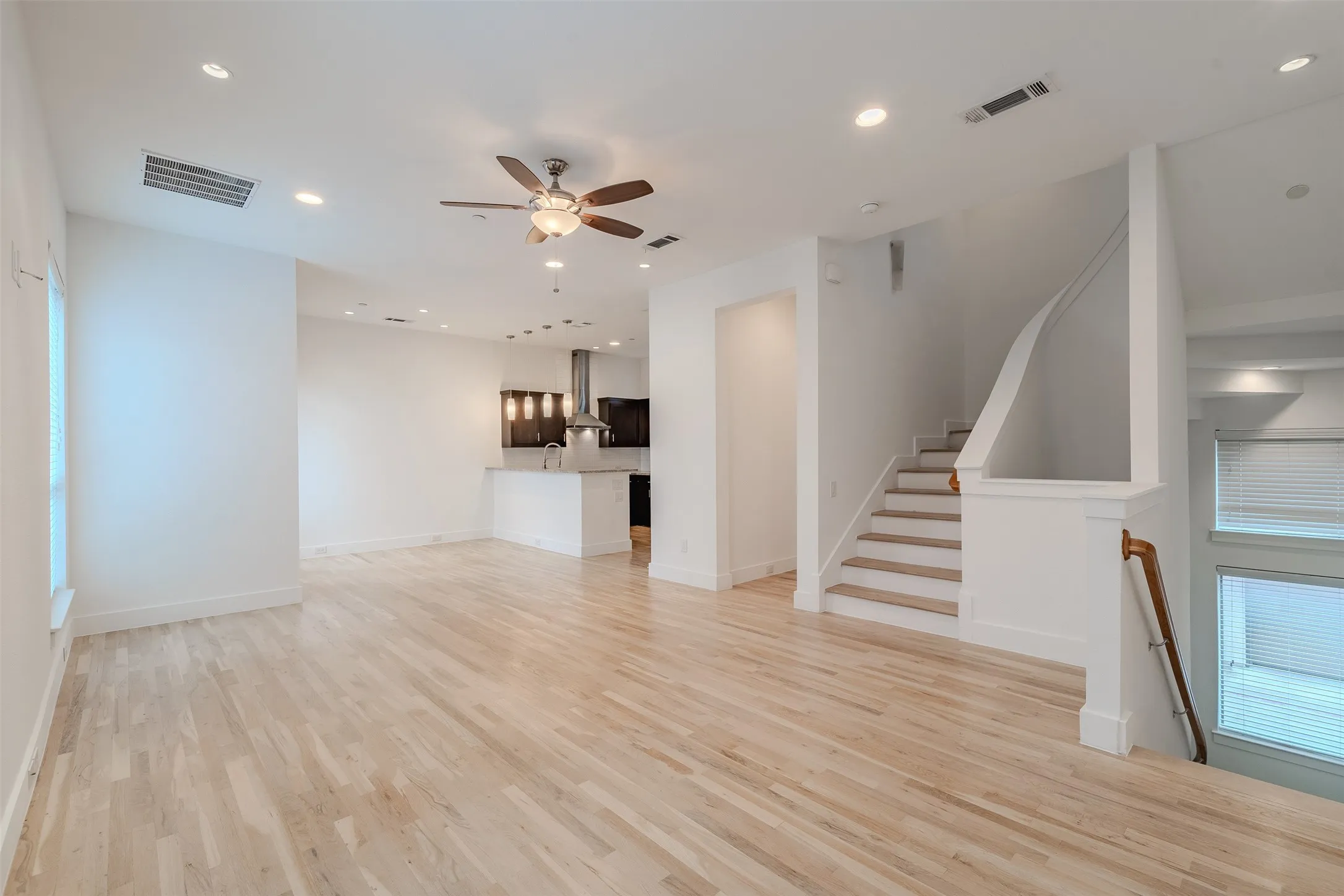 Light wood-finish flooring throughout, recessed lighting, and a ceiling fan with integrated lighting