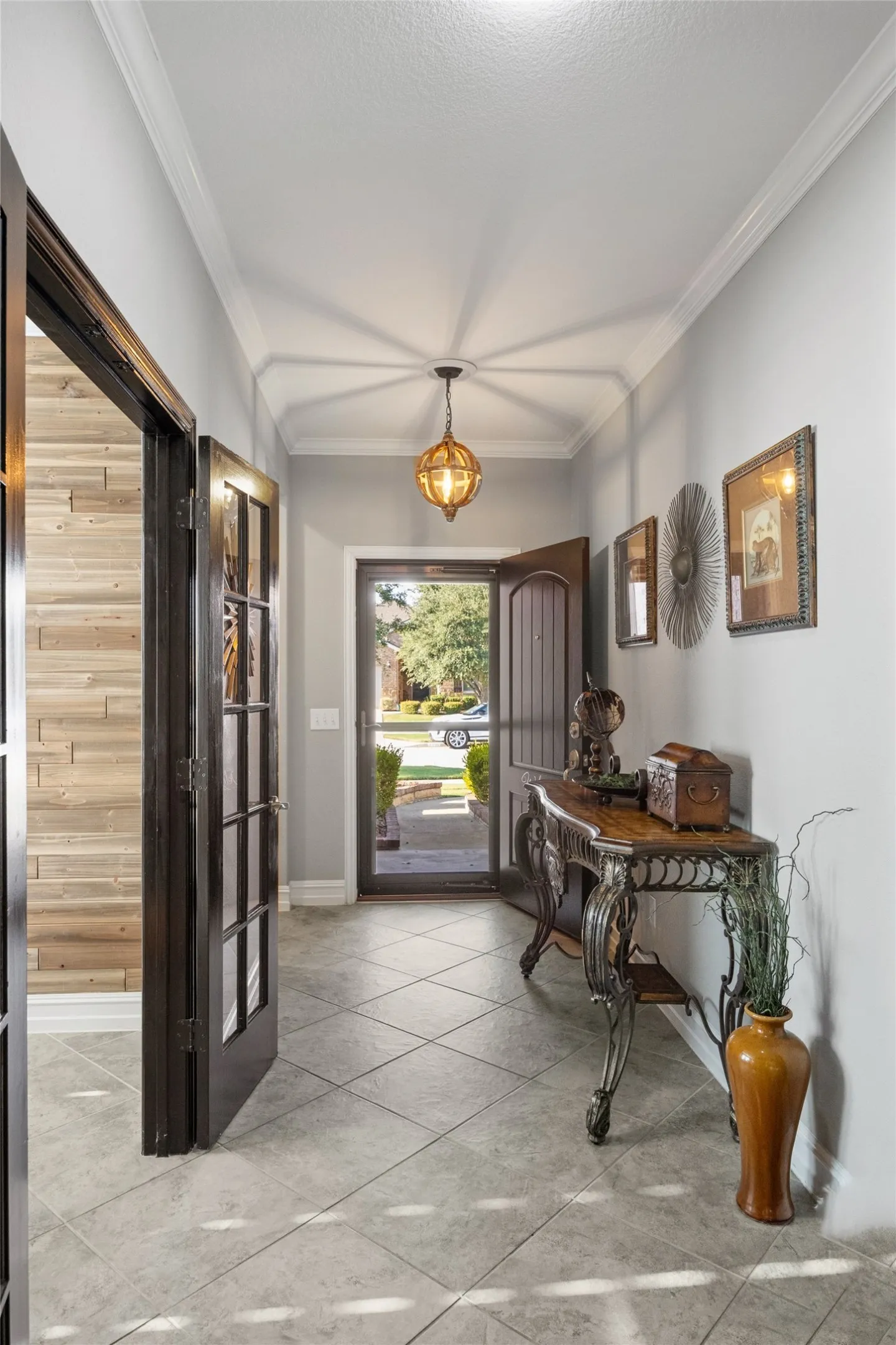 Foyer featuring diagonal tile flooring, dark wood-finish French doors, and crown molding
