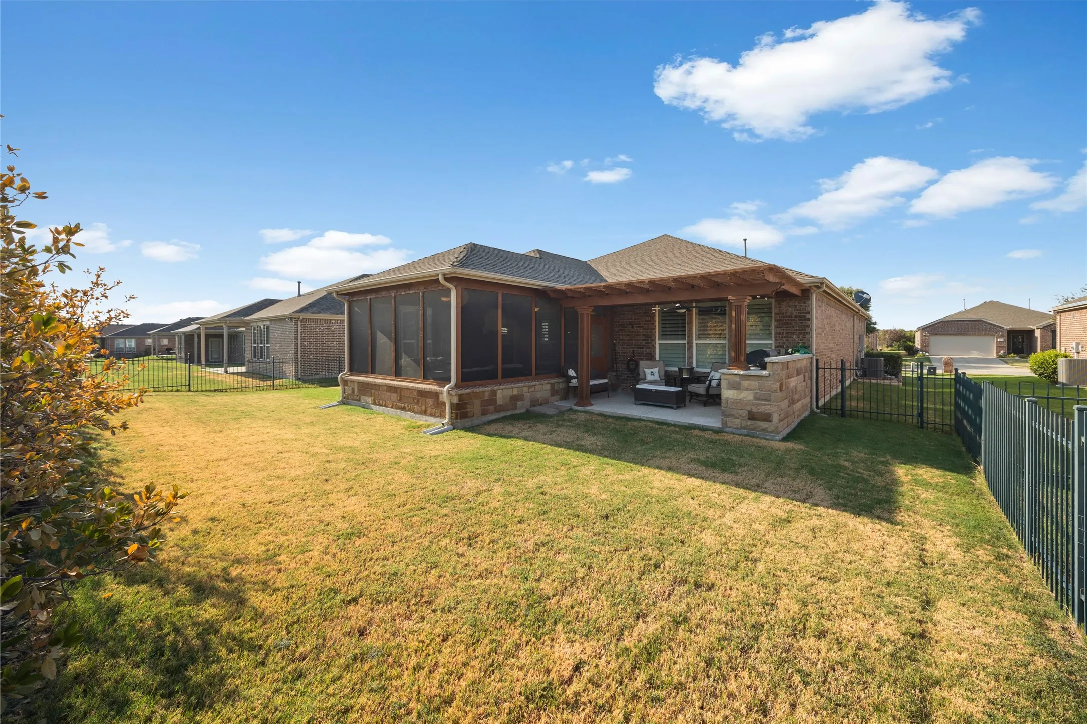 Brick exterior with a covered patio, screened porch, and fenced backyard