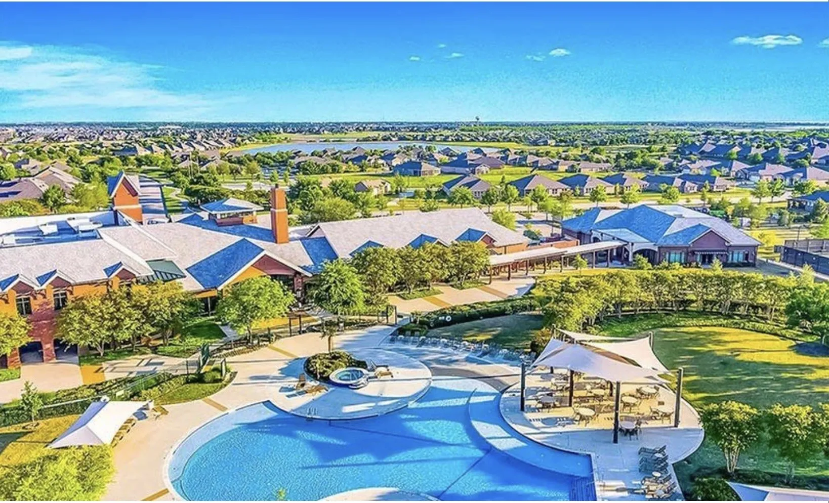 Expansive community grounds featuring a swimming pool, shaded outdoor seating, and a large central building with multiple wings