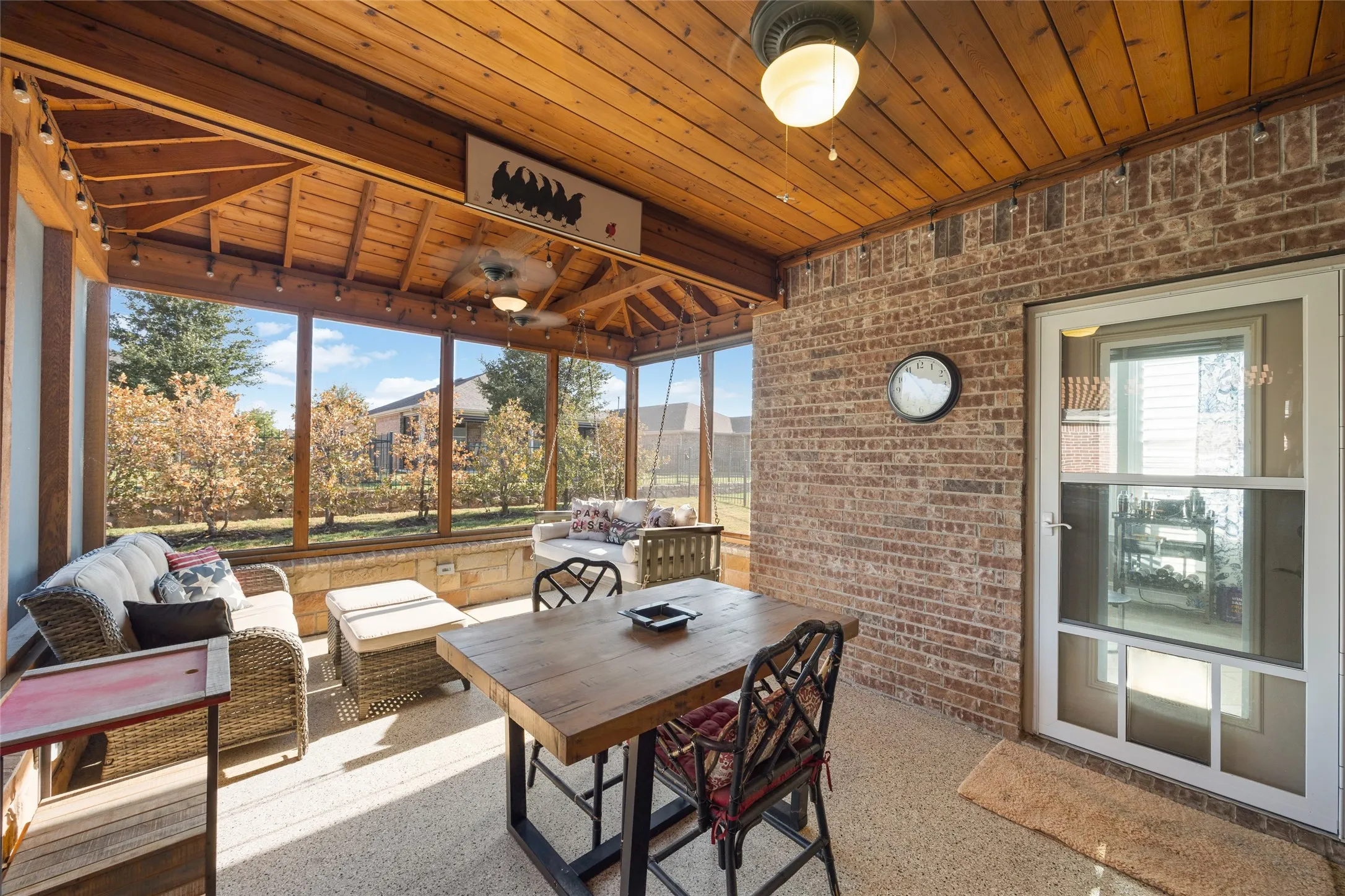 Screened-in porch featuring a natural wood plank ceiling, exposed brick wall, and a wood-finish floor