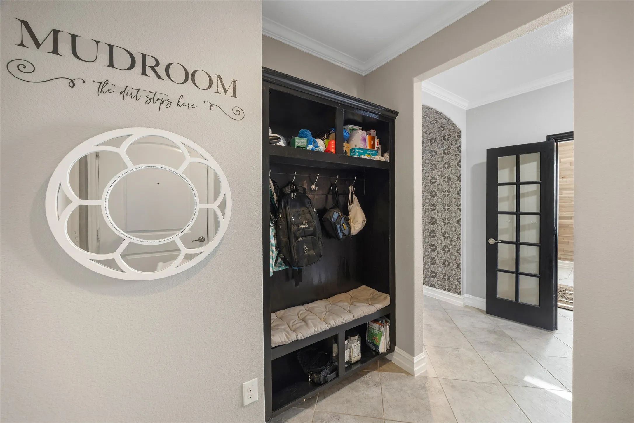 Built-in hall tree with storage, tile flooring, and a decorative mirror