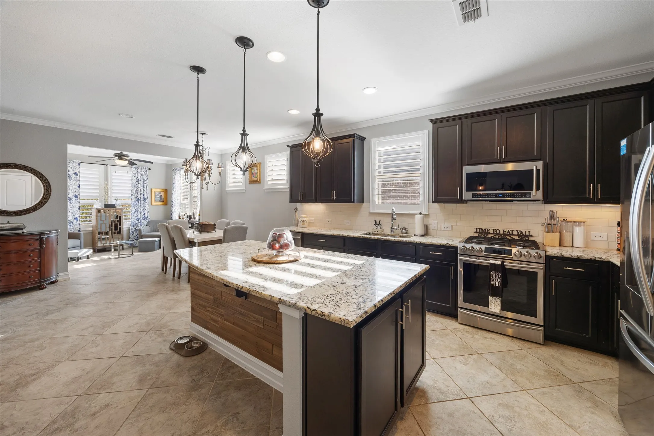 Kitchen featuring dark wood cabinetry, stainless steel appliances, granite countertops, and a tile backsplash
