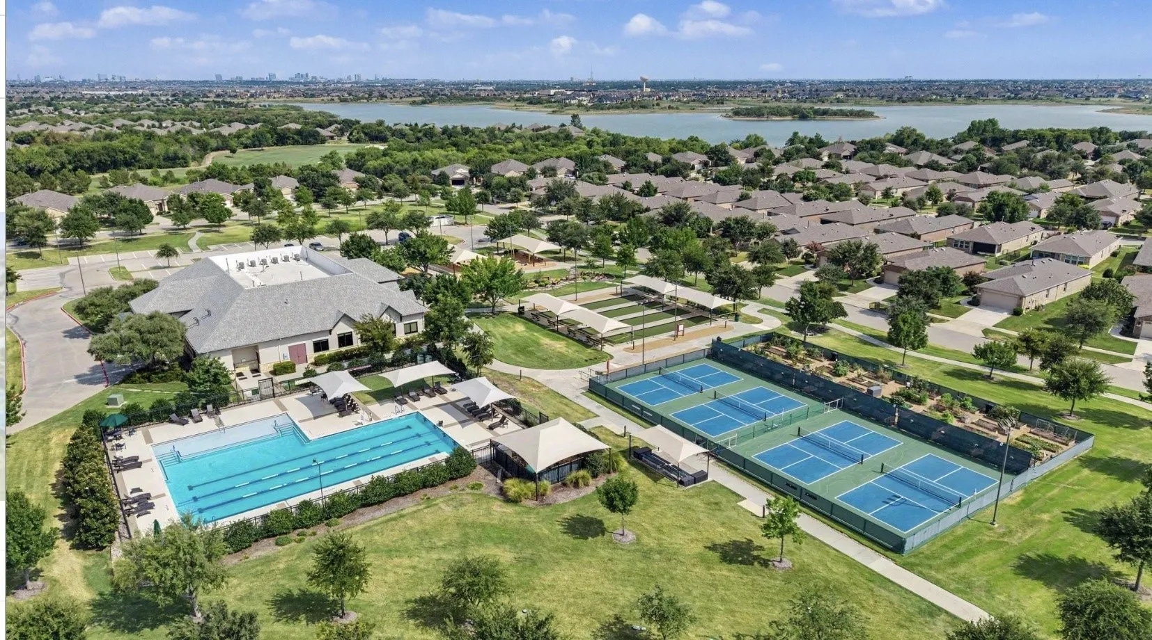 Community clubhouse with an outdoor swimming pool, multiple tennis courts, and landscaped grounds