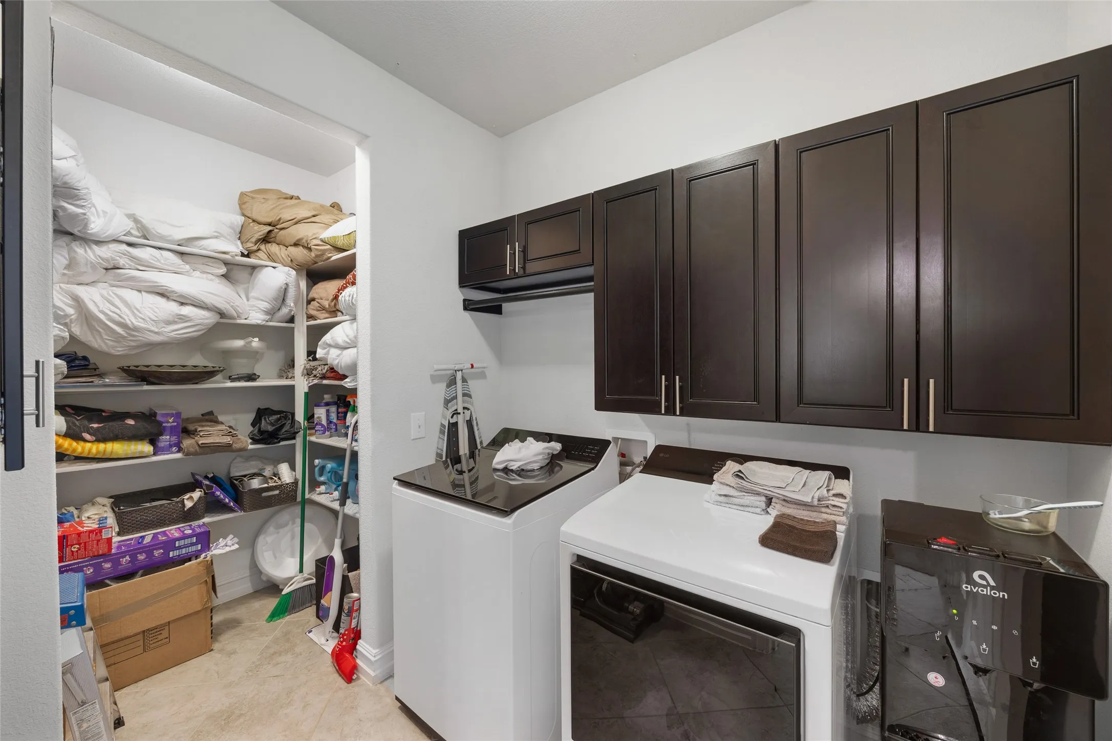 Built-in dark wood-finish cabinetry, tile flooring, and dedicated storage closet with shelving