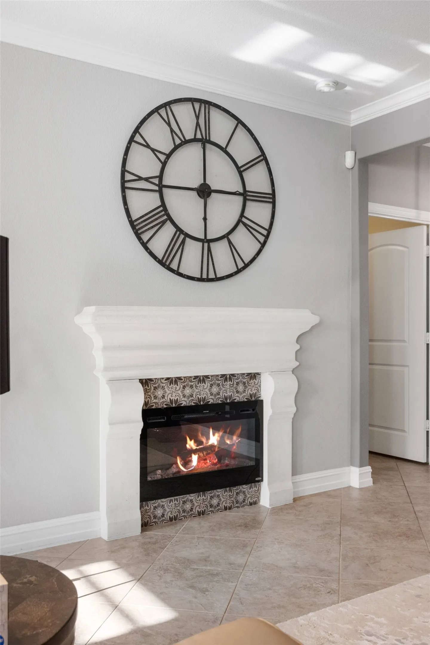 Fireplace with a decorative mantel, patterned tile surround, and a glass-front insert