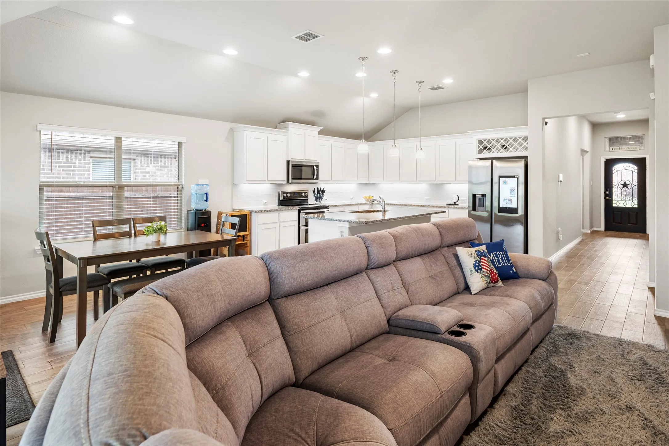 Open-concept living space featuring vaulted ceilings, recessed lighting, and wood-finish flooring