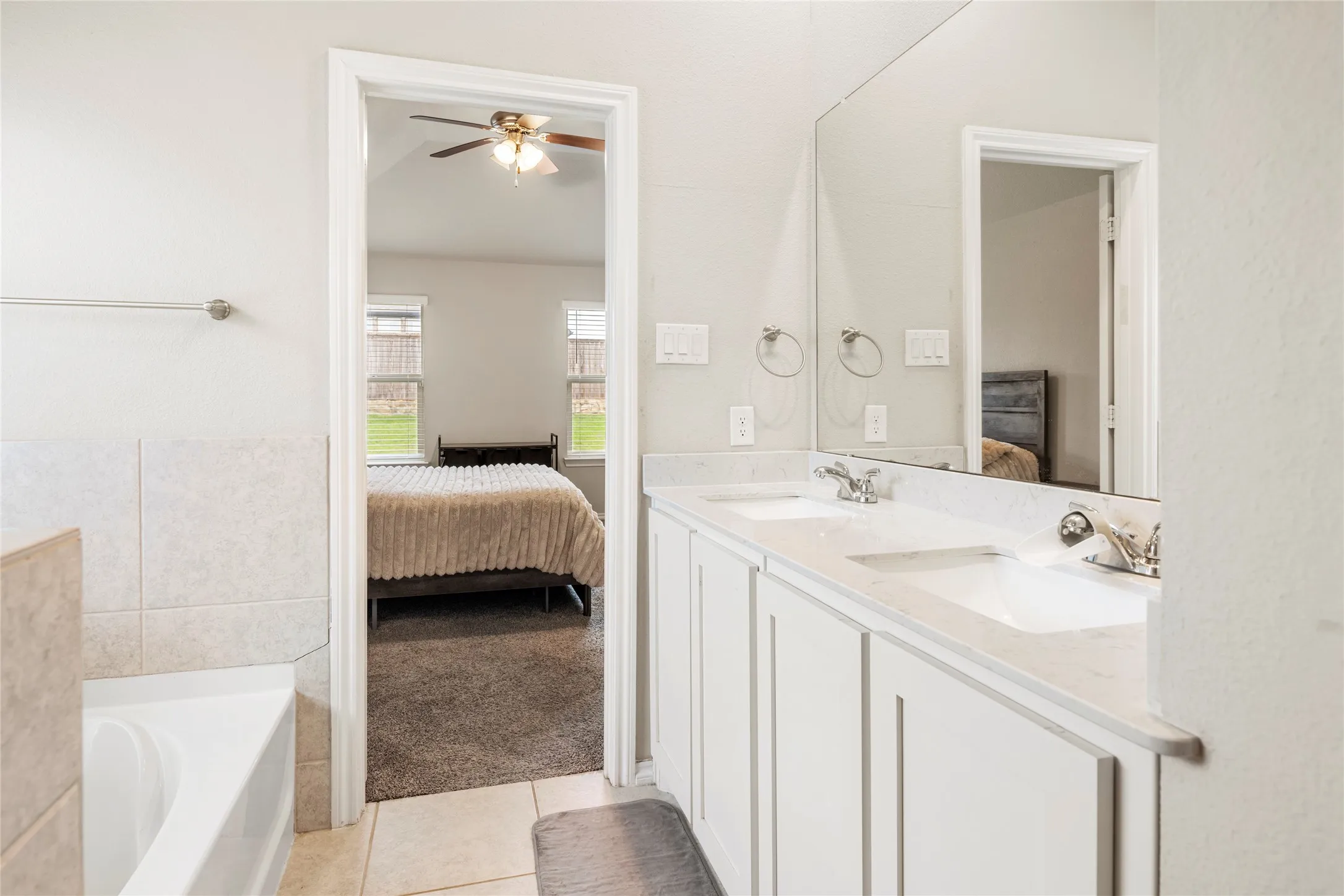 Dual vanity with integrated sinks, full-width mirror, white cabinetry just off primary....