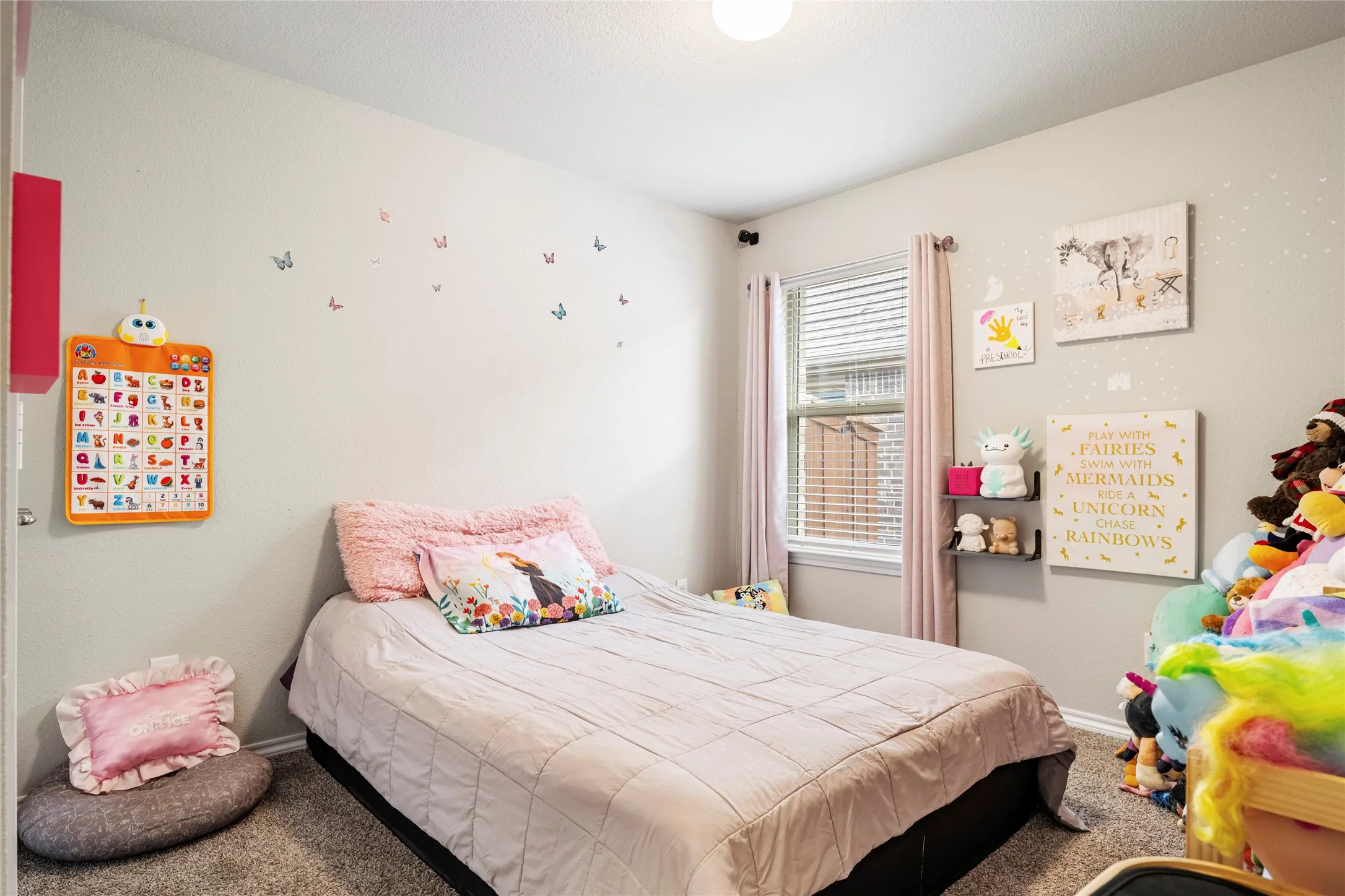 2nd bedroom featuring a window with blinds, decorative lighting fixture, and neutral wall paint...