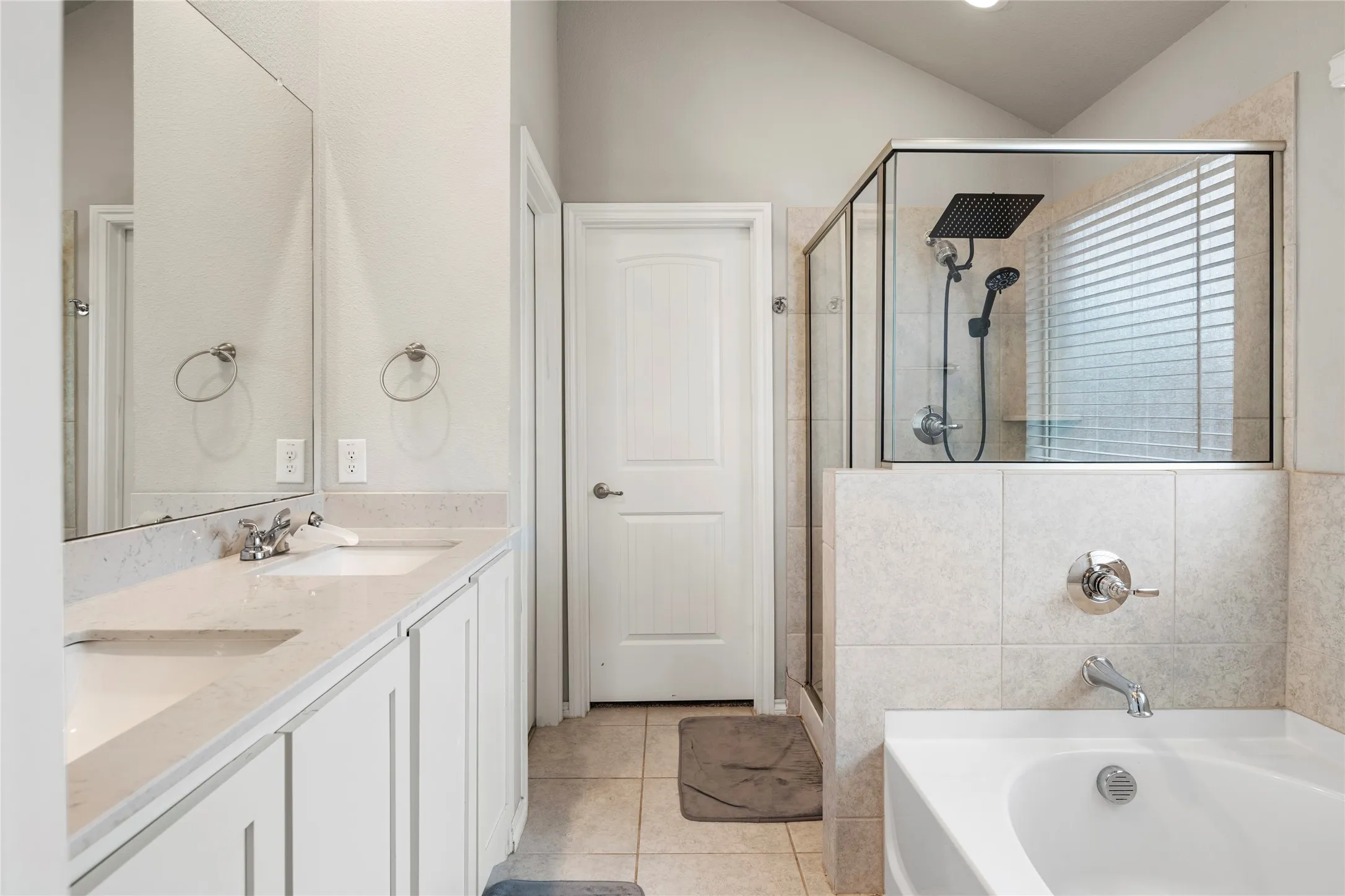 Dual vanity with undermount sinks, a built-in soaking tub, a tiled shower enclosure with glass panels, and a rain shower head and a separate water closet....