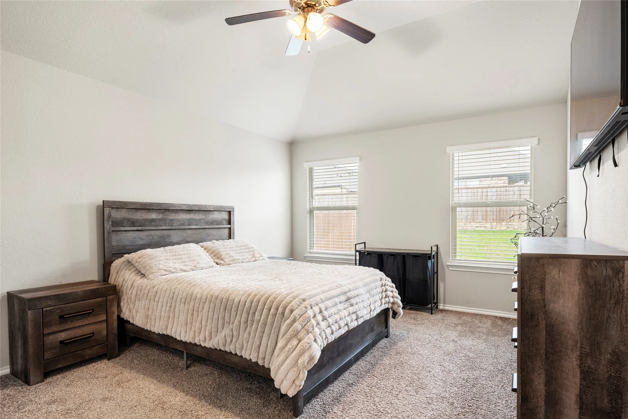 Great size primary with vaulted ceiling, a ceiling fan, windows with blinds, and neutral carpeting....