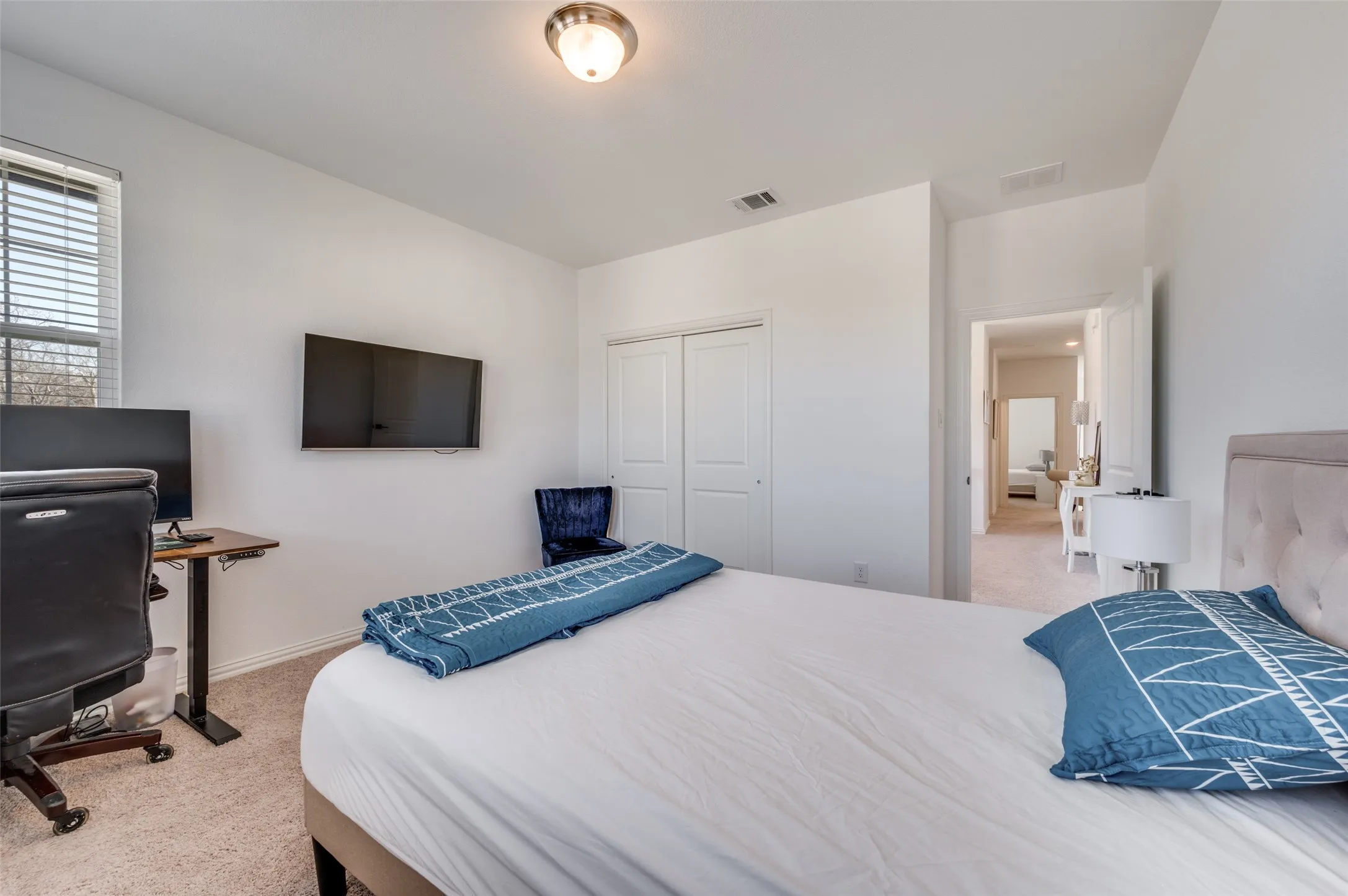 Carpeted bedroom with a window featuring blinds, a ceiling-mounted light fixture, and double-door closet