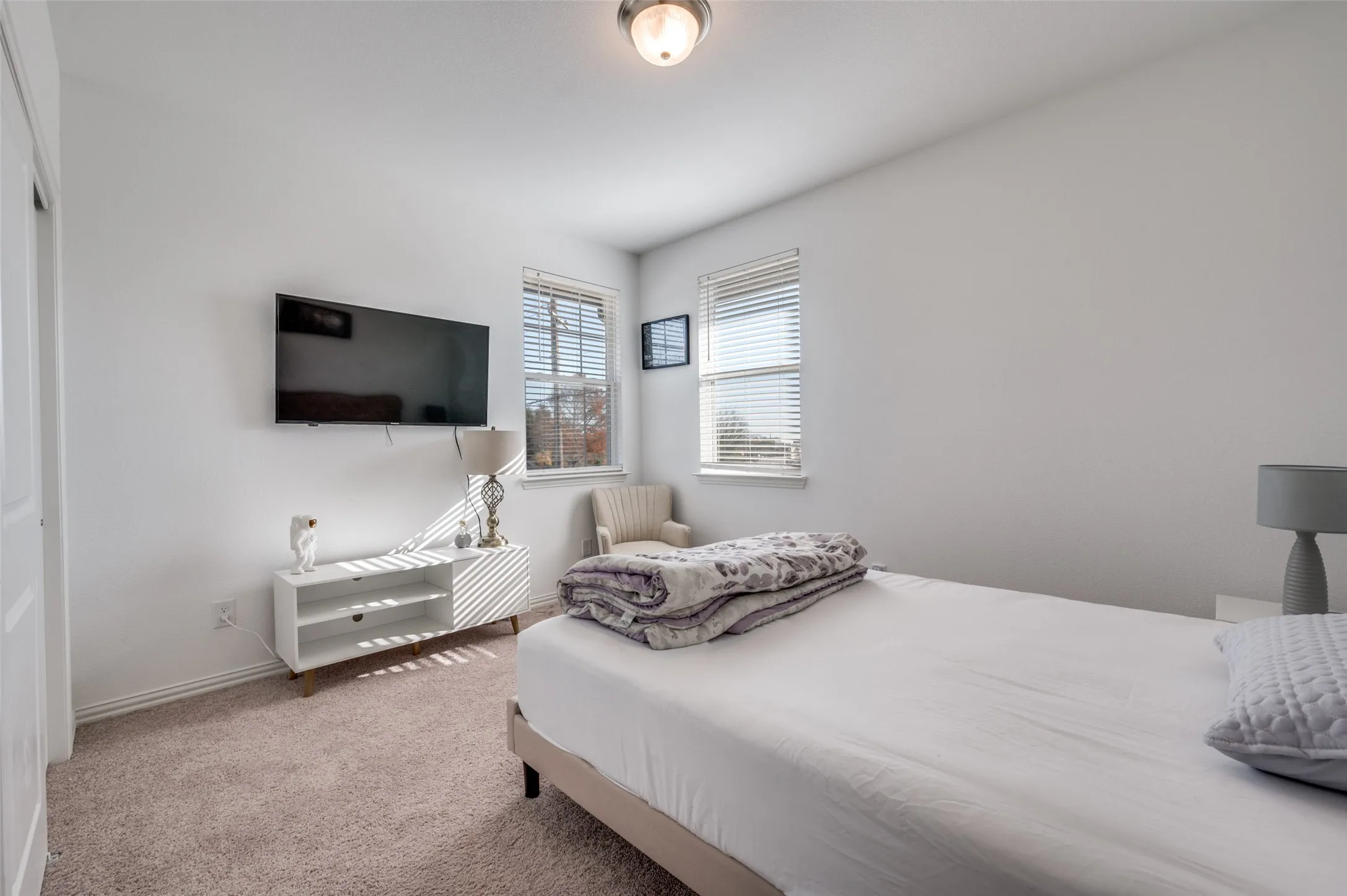 Carpeted flooring, white painted walls, and two windows with blinds