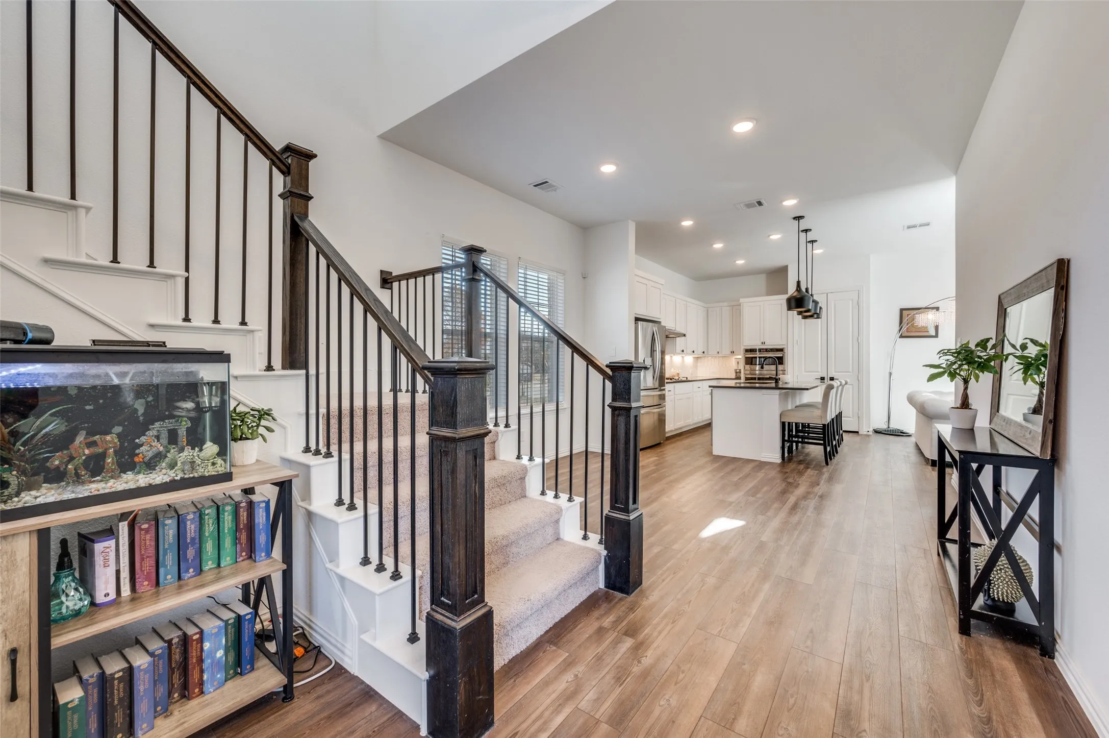 Open-concept living area with wood-finish flooring, white walls, and recessed lighting