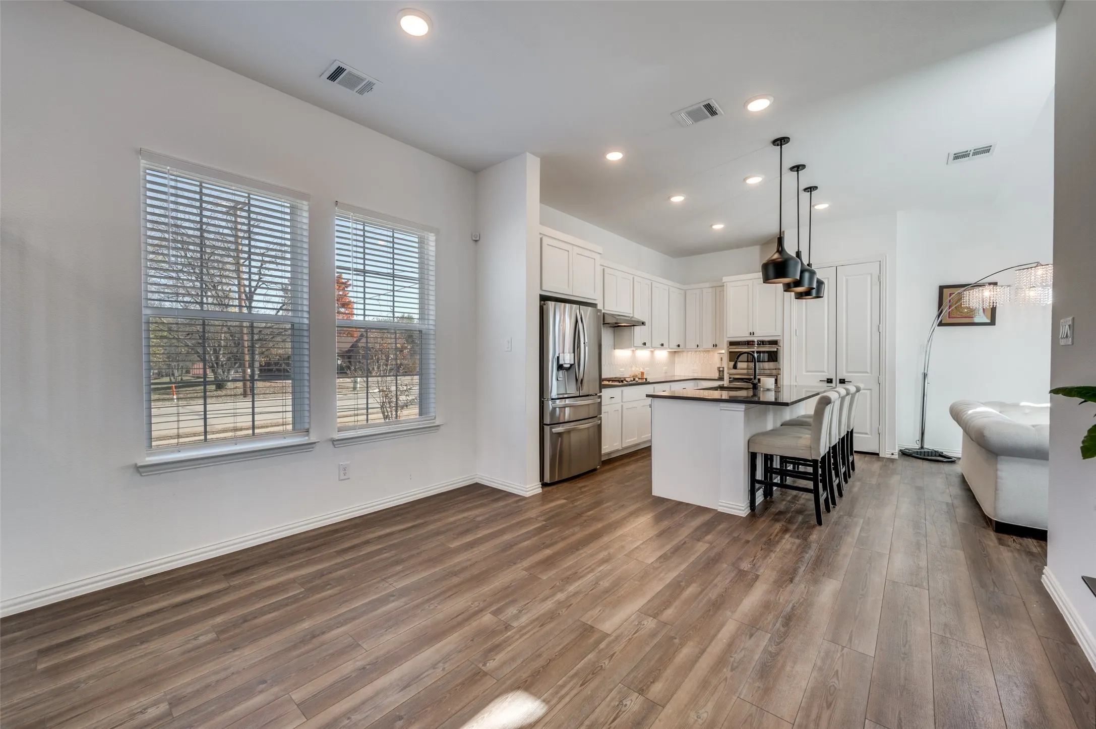 Kitchen featuring white cabinetry, stainless steel appliances, a dark countertop island, and pendant lighting